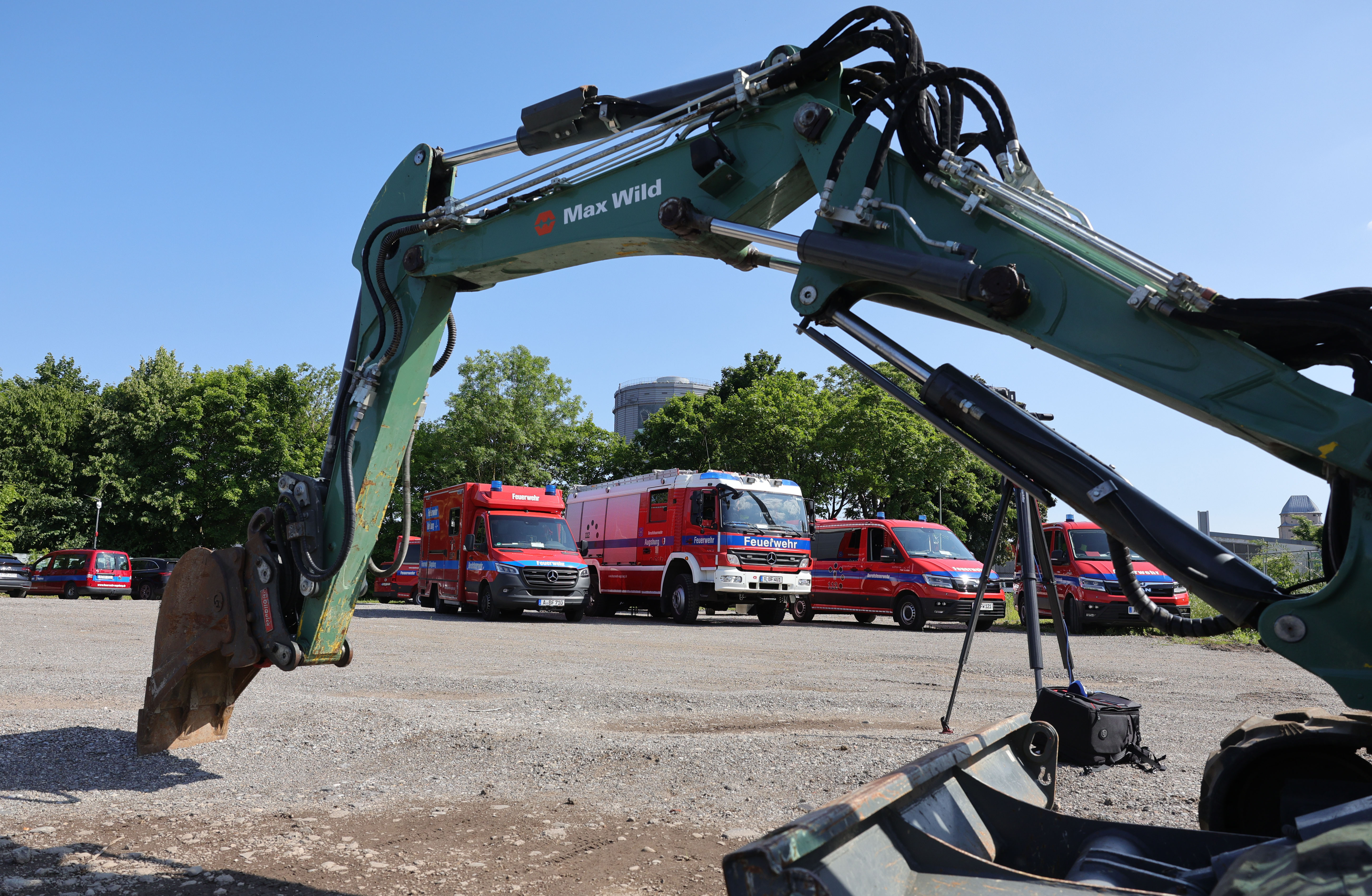 im Hintergrund verschiedene Feuerwehrfahrzeuge, im Vordergrund ein Bagger mit Schaufel
