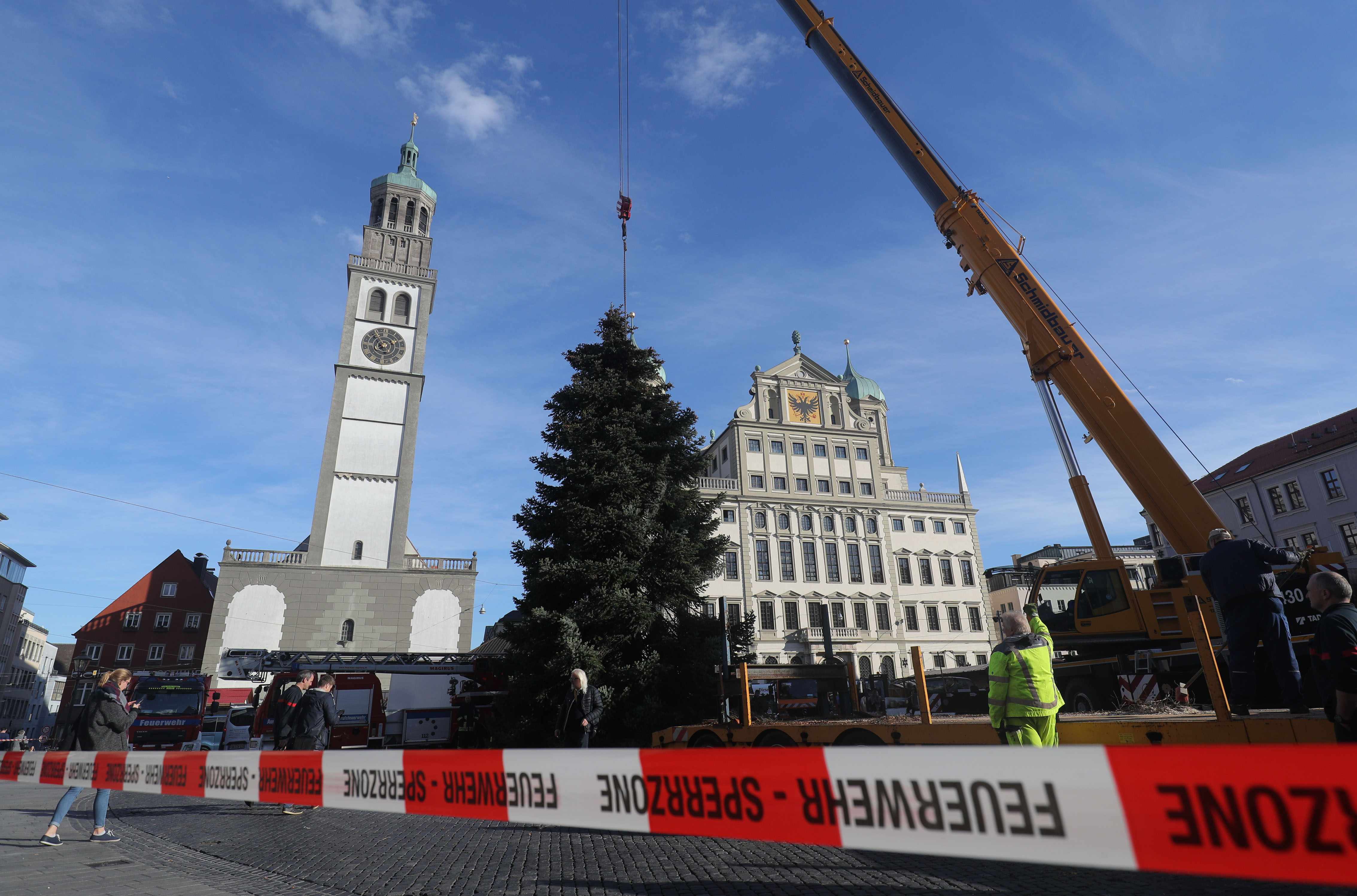 im Vordergrund Trassierband mit der Aufschrift "Feuerwehr" dahinter ein an einem Kran hängender großer Nadelbaum vor der Kulisse von Perlachturm und Rathaus