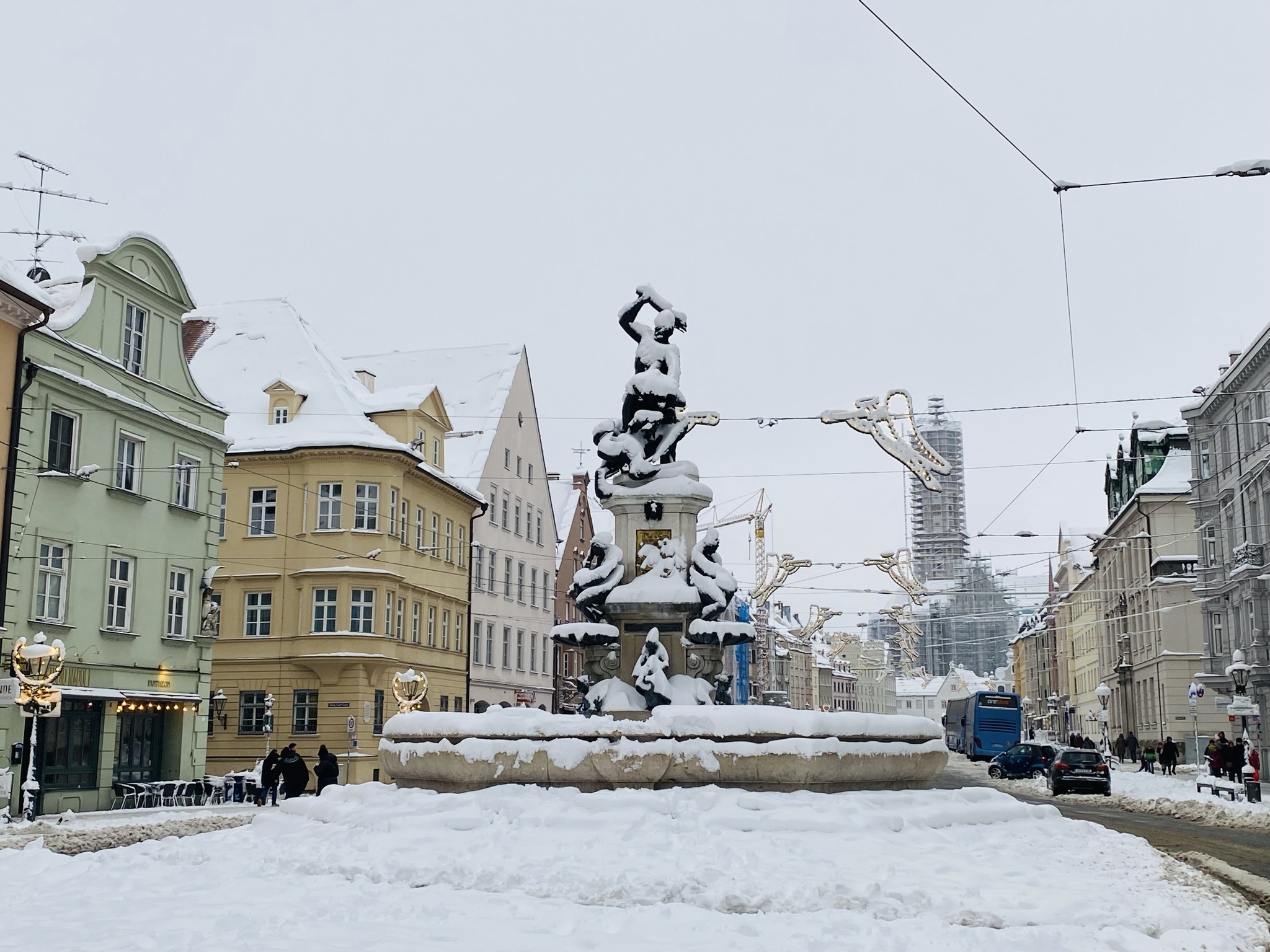 Herkulesbrunnen mit Schnee bedeckt, im Hintergrund St. Ulrich
