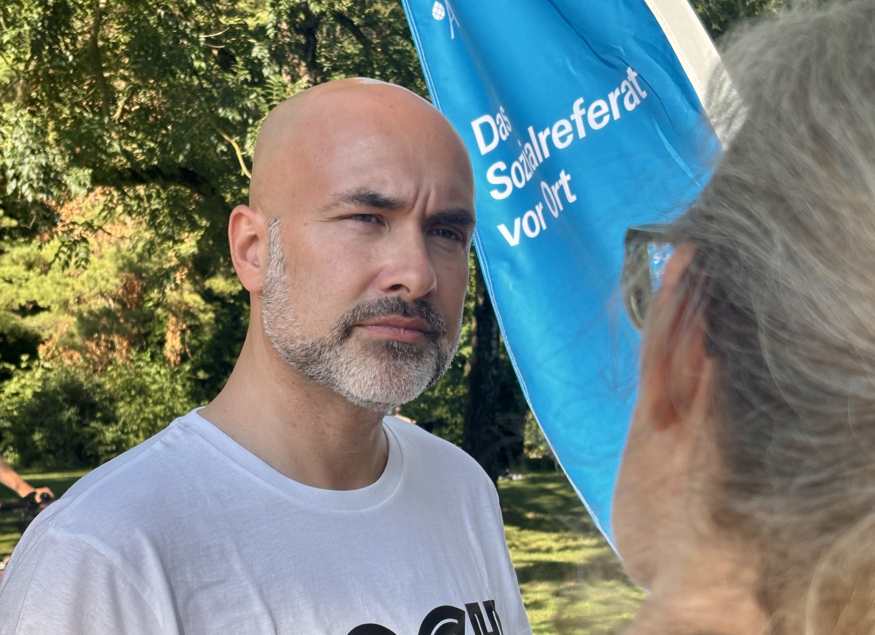 Sozialreferent Martin Schenkelberg im T-Shirt im Gespräch mit einer Frau.