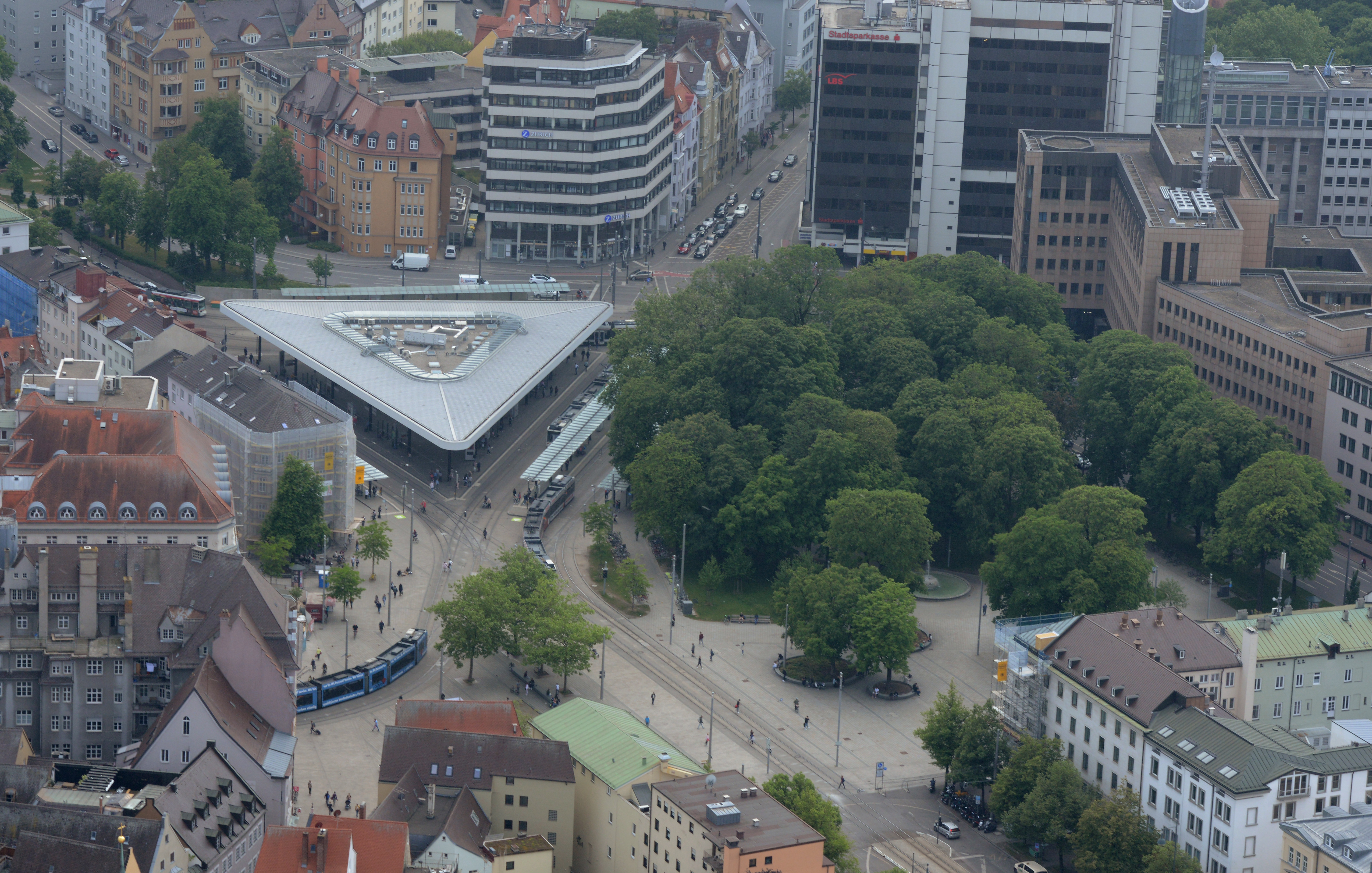 Das Luftbild zeigt den Königsplatz und die umliegenden Straßen von oben. Zu sehen sind mehrere Autos, Busse und Straßenbahnen, aber auch zahlreiche Fußgänger.