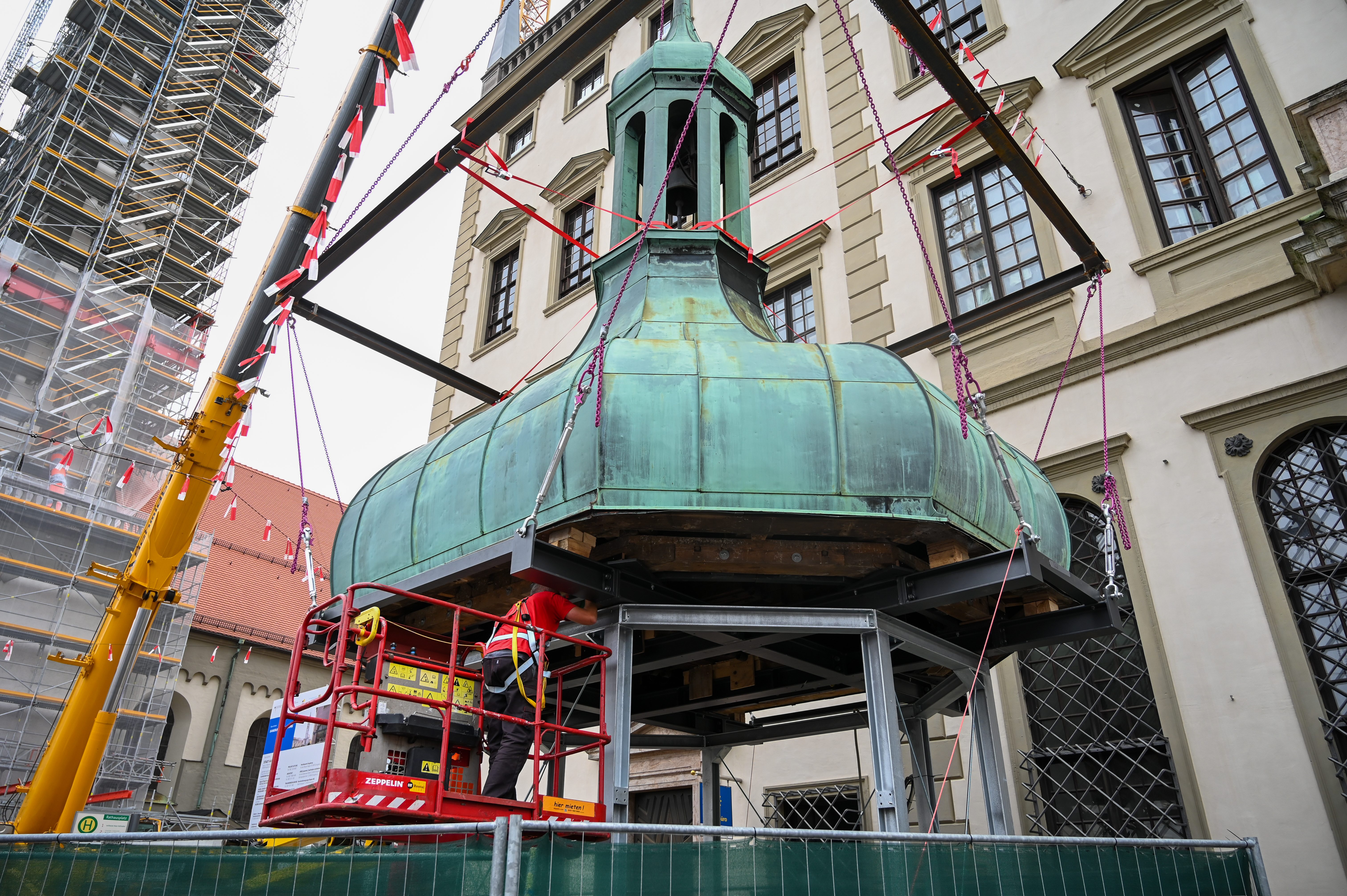 Handwerker befestigen eine Turmkuppel auf einem Metallgerüst