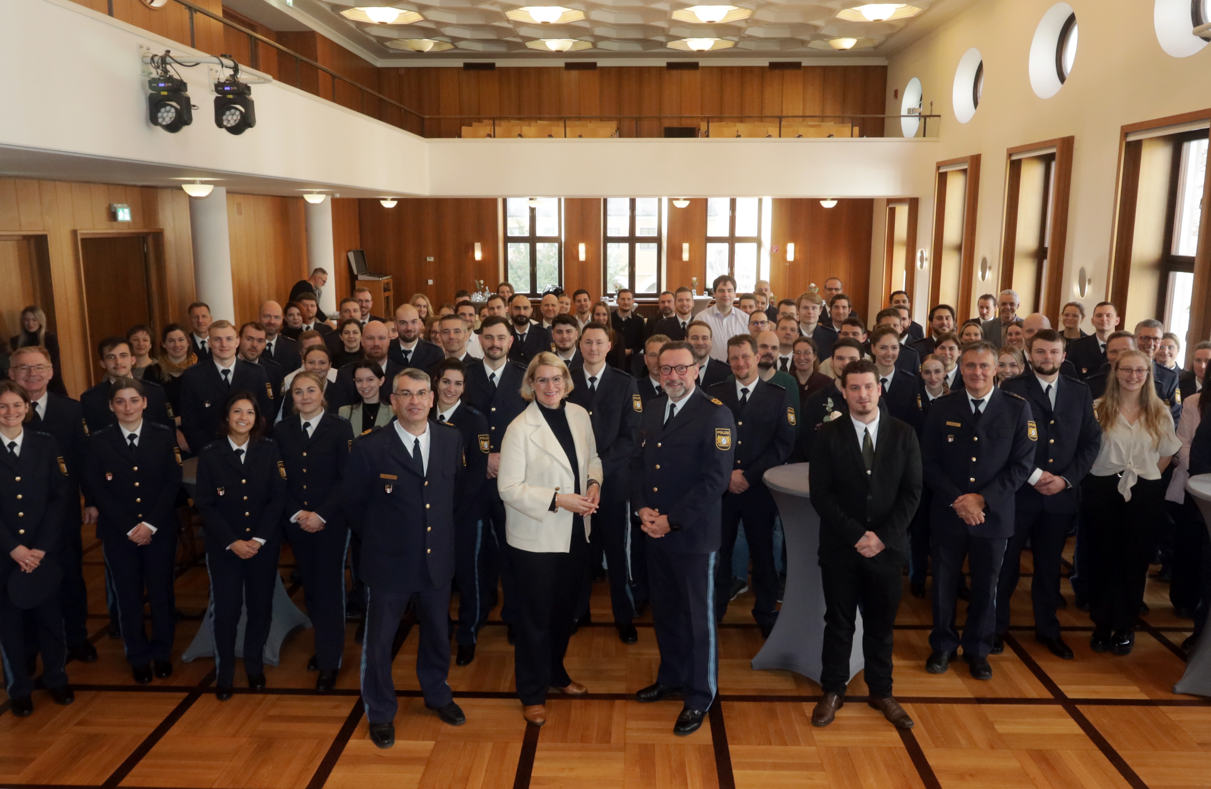 Etwa 100 Leute in einem Saal. Die meisten Personen tragen eine Polizeiuniform