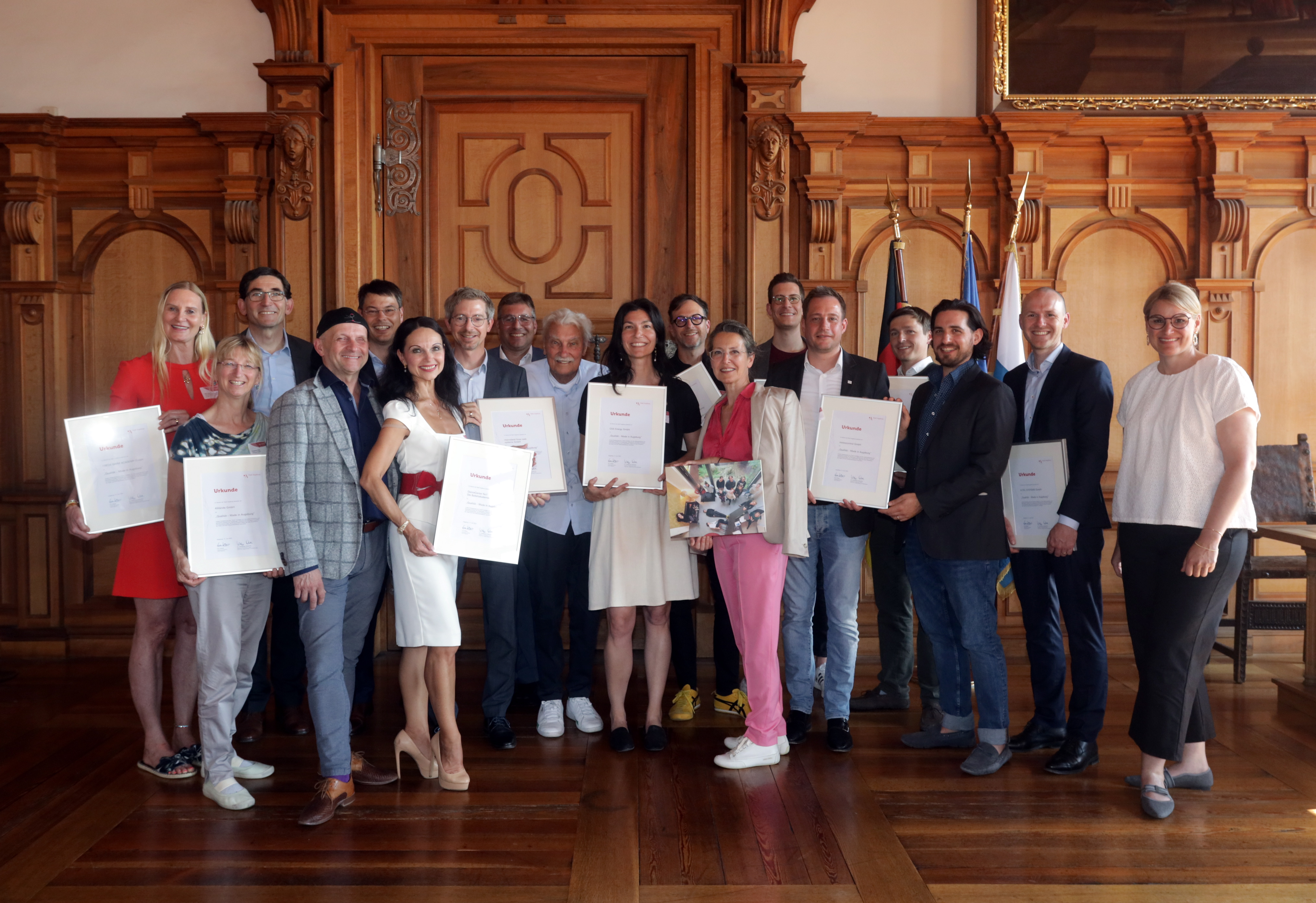 Knapp 20 Personen stehen im Fürstenzimmer des Rathauses. Einige halten Urkunden in der Hand. Ganz rechts steht Oberbürgermeisterin Eva Weber. Die Wand im Hintergrund ist mit Holz vertäfelt