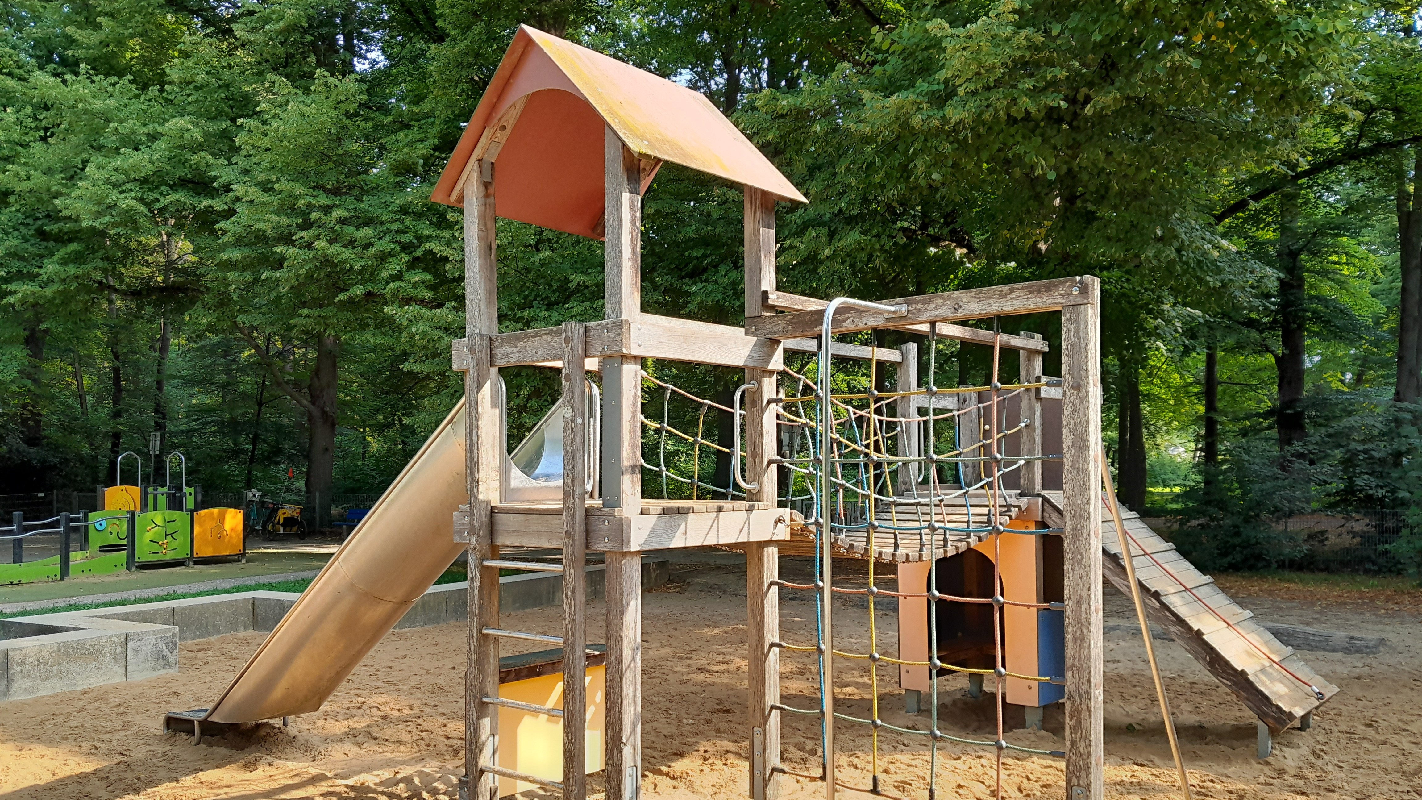 Ein Spielhaus mit Rutsche und Kletter-Netz auf einem Spielplatz