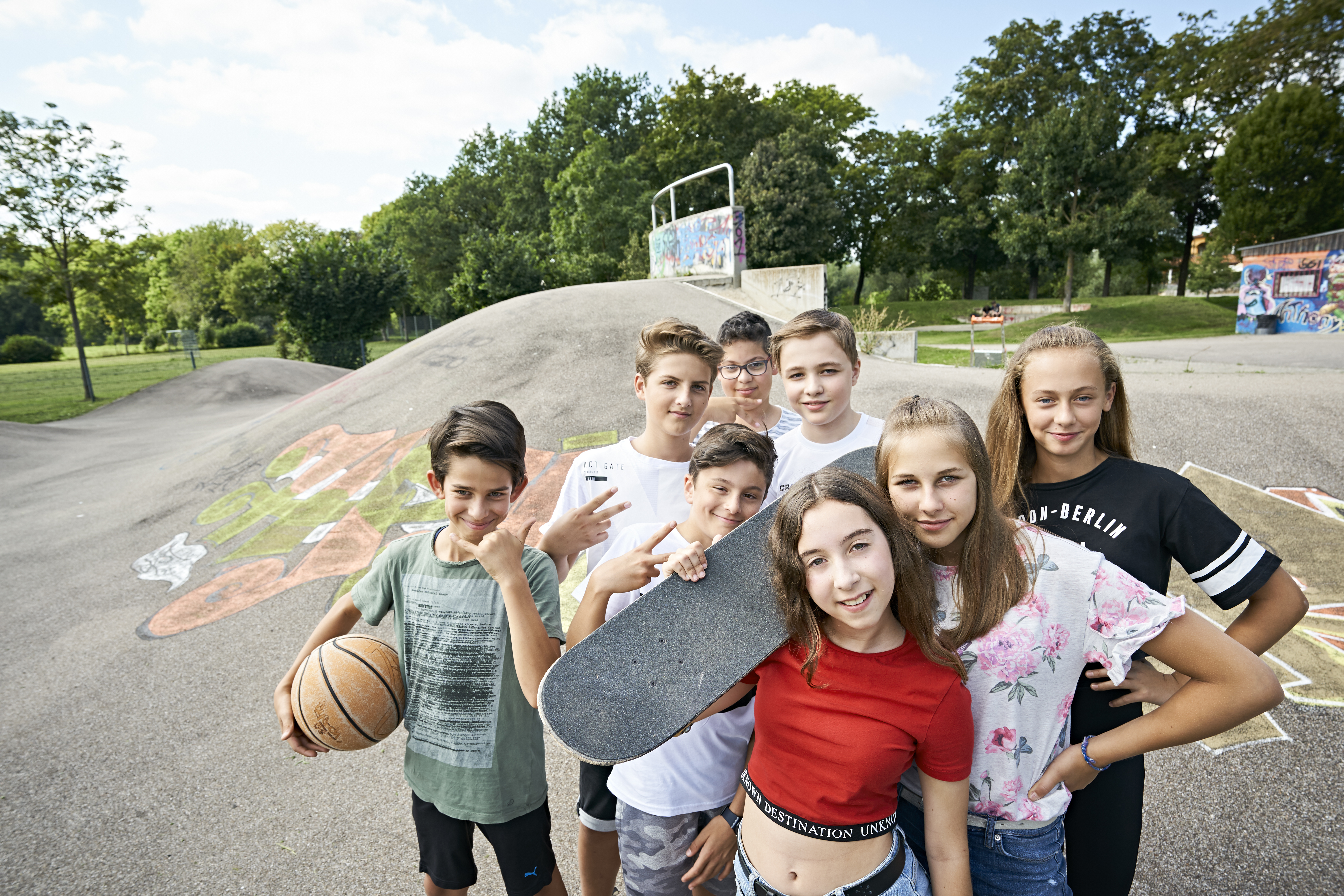 Kinder auf einem Skaterplatz, alle sehen in die Kamera