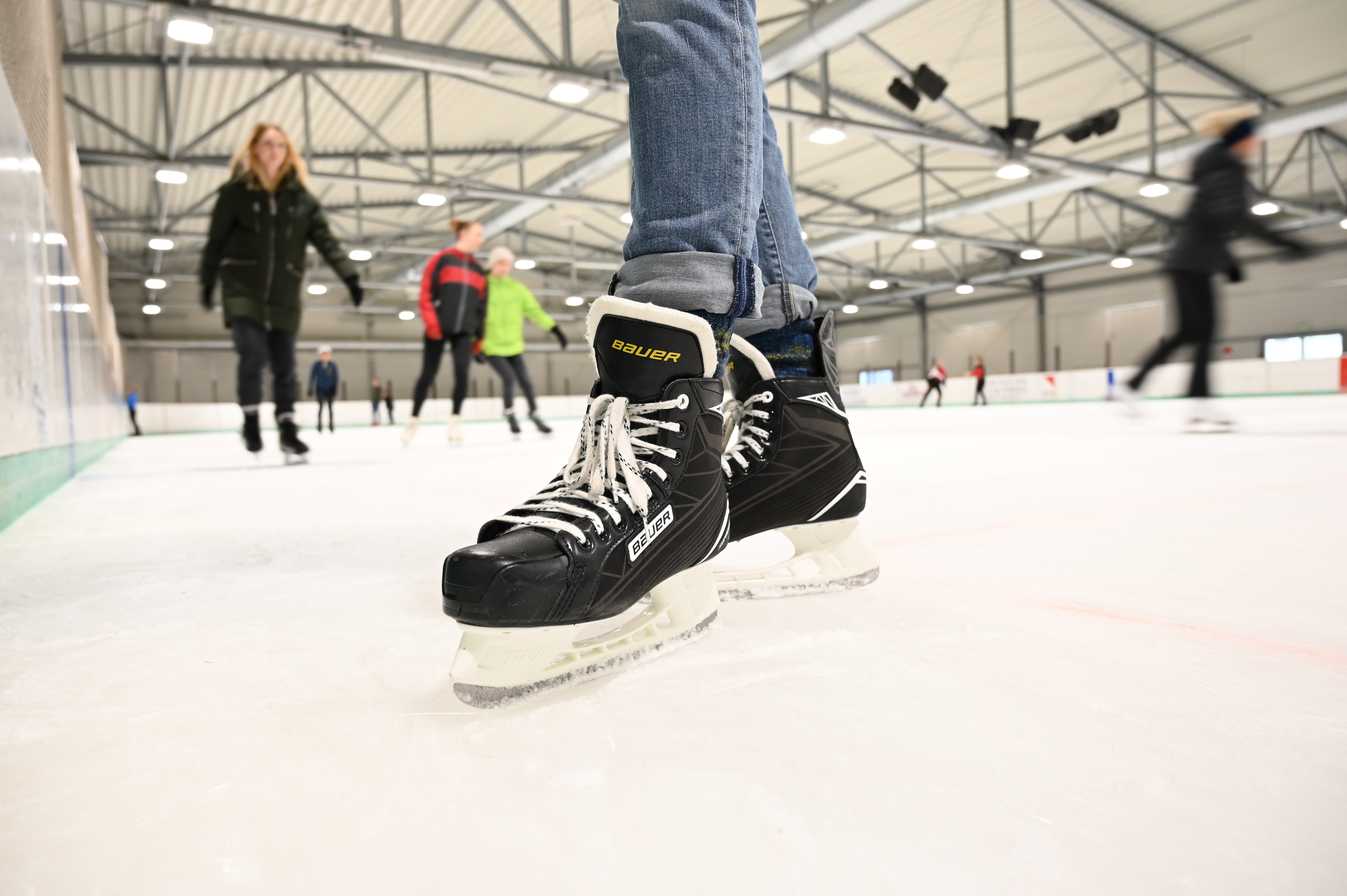 Etwa 10 Leute laufen Schlittschuh in einer Eishalle