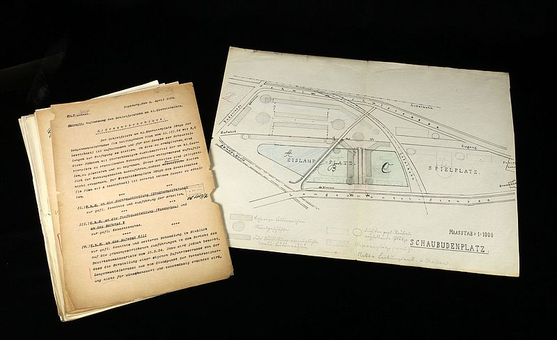 Plan zur Umgestaltung der Eislauffläche am Kleinen Exerzierplatz zu einem Schaubudenplatz; undatiert [1925]; gedruckter Plan, Papier, Eintragungen mit Farb- und Bleistift, 42 cm h x 34 cm b u. Begleitakten, 34 cm h x 22 cm b; Stadtarchiv Augsburg, Bestand 19, Nr. 9.