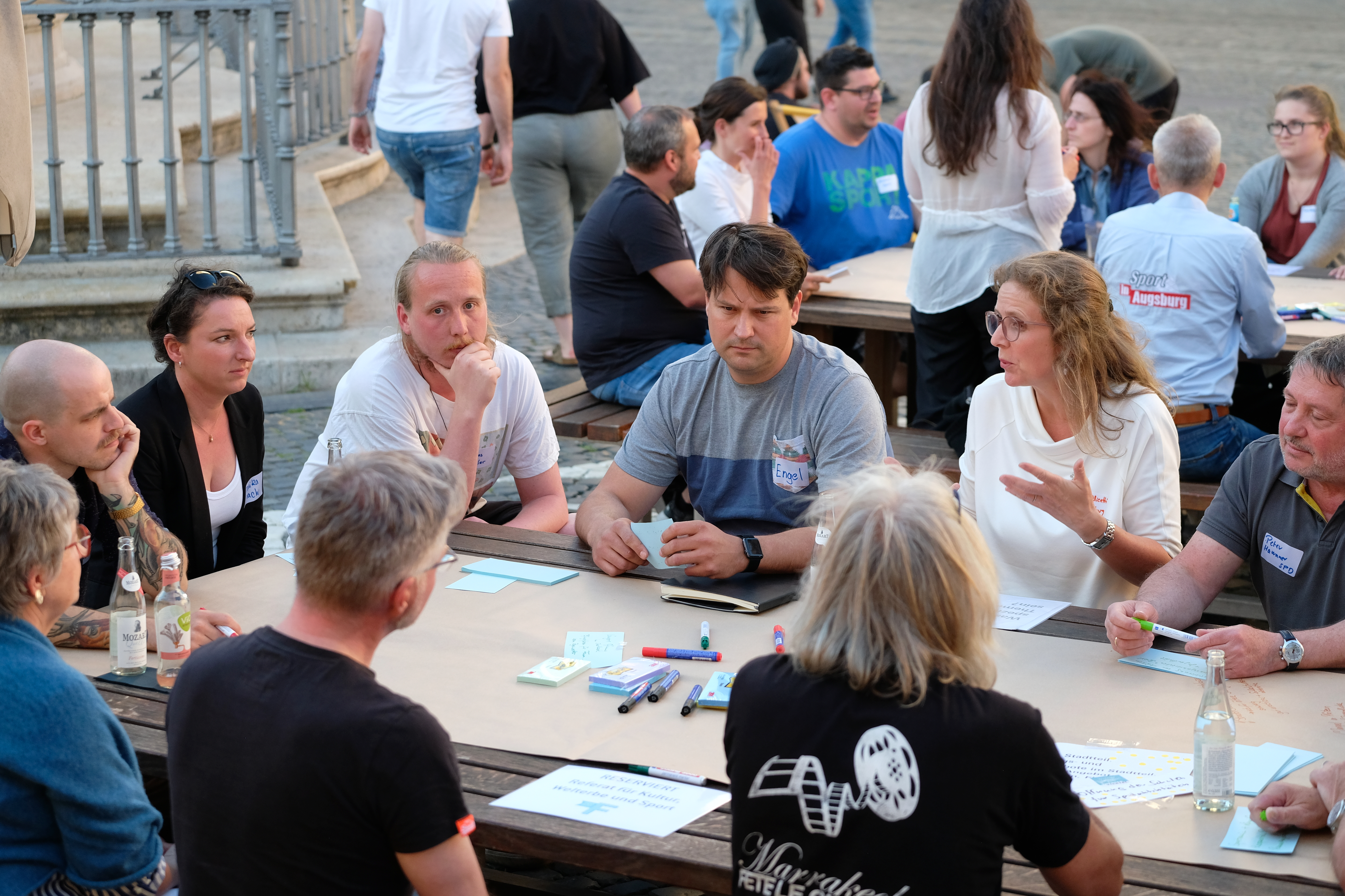 Etwa 30 Menschen sitzen in einem Raum und diskutieren