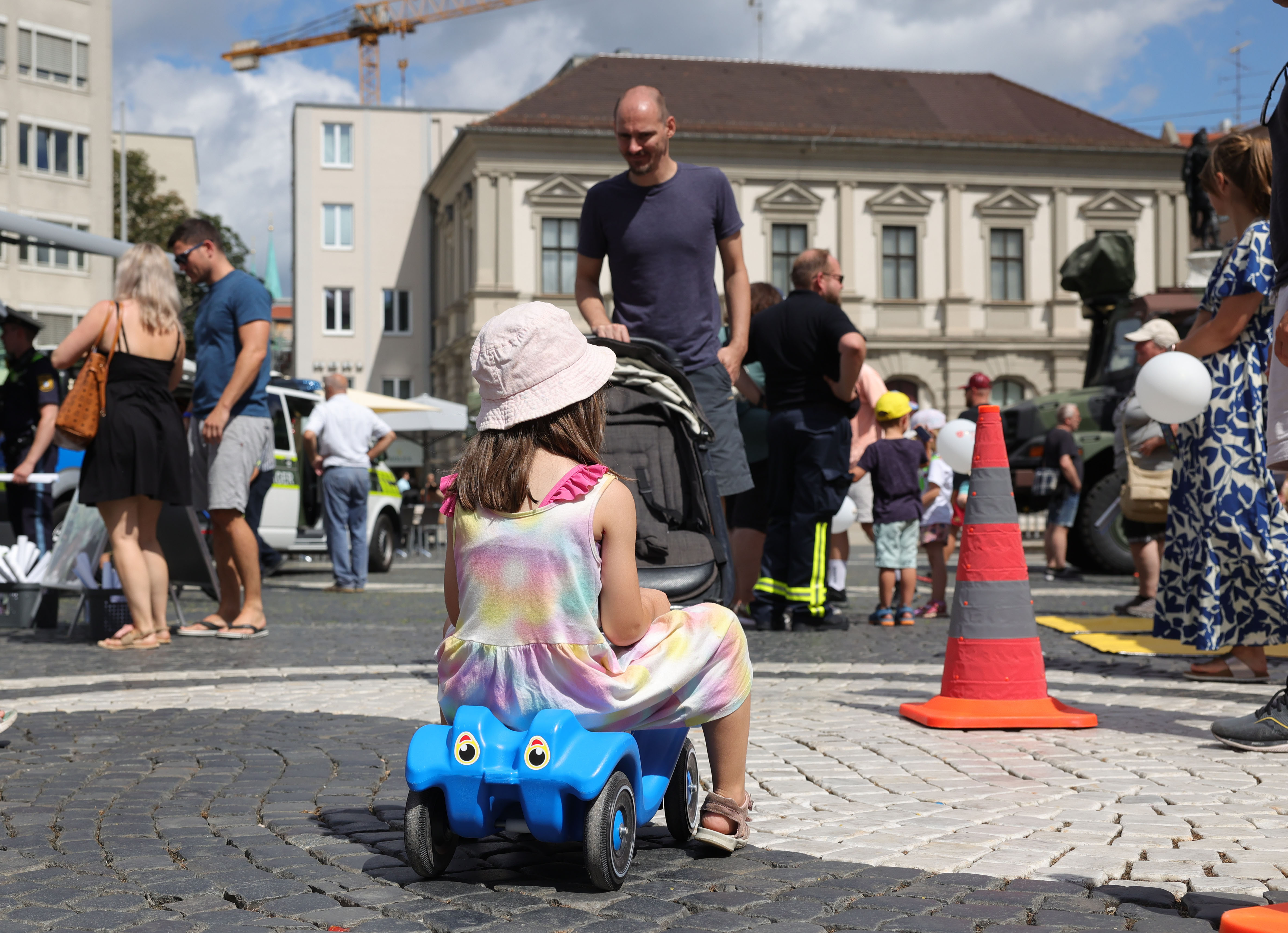 Mädchen auf Bobbycar von hinten gesehen; links vor ihr eine Ampel