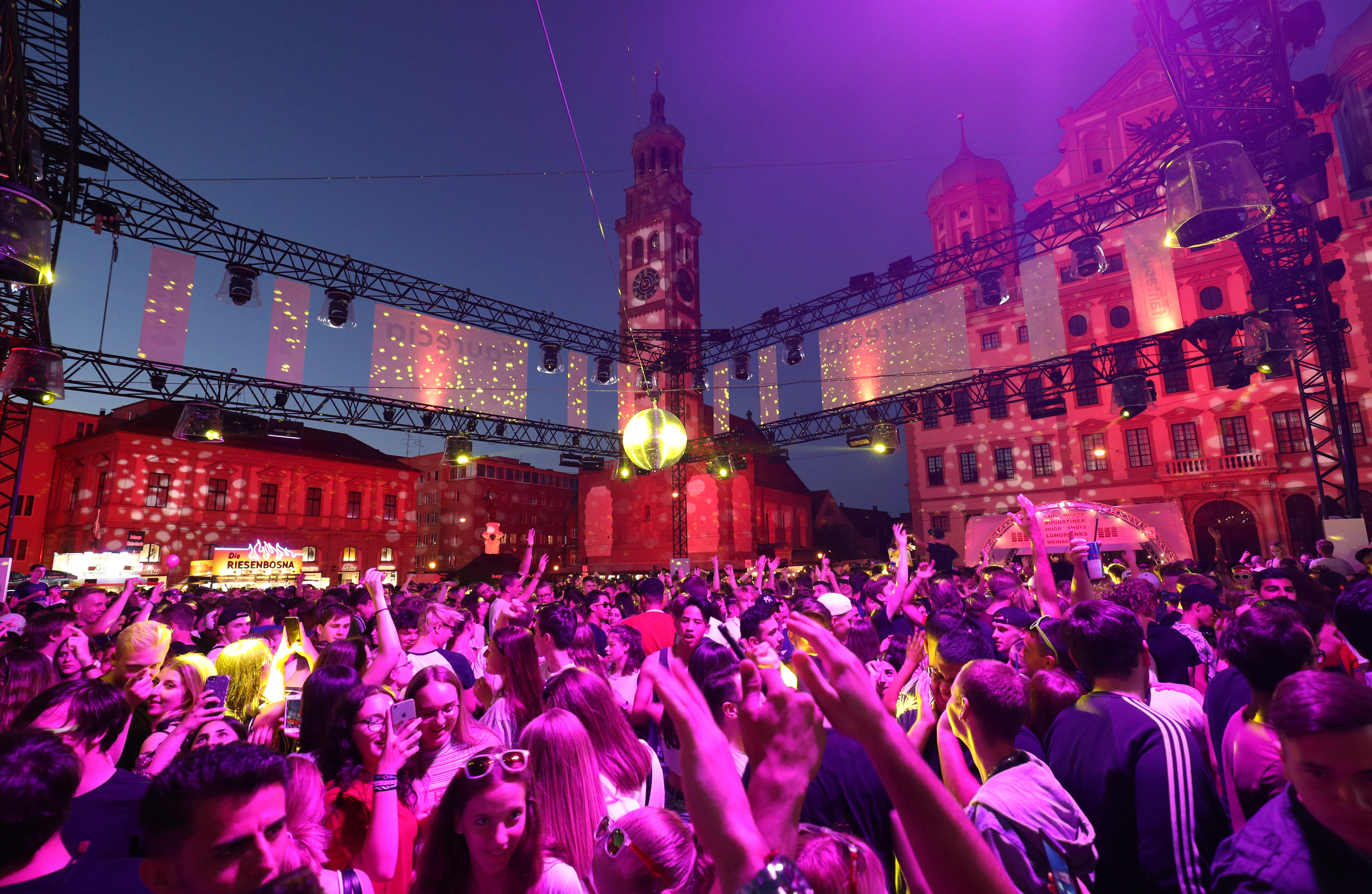 Hunderte junge Leute tanzen bei Nacht auf dem beleuchteten Rathausplatz