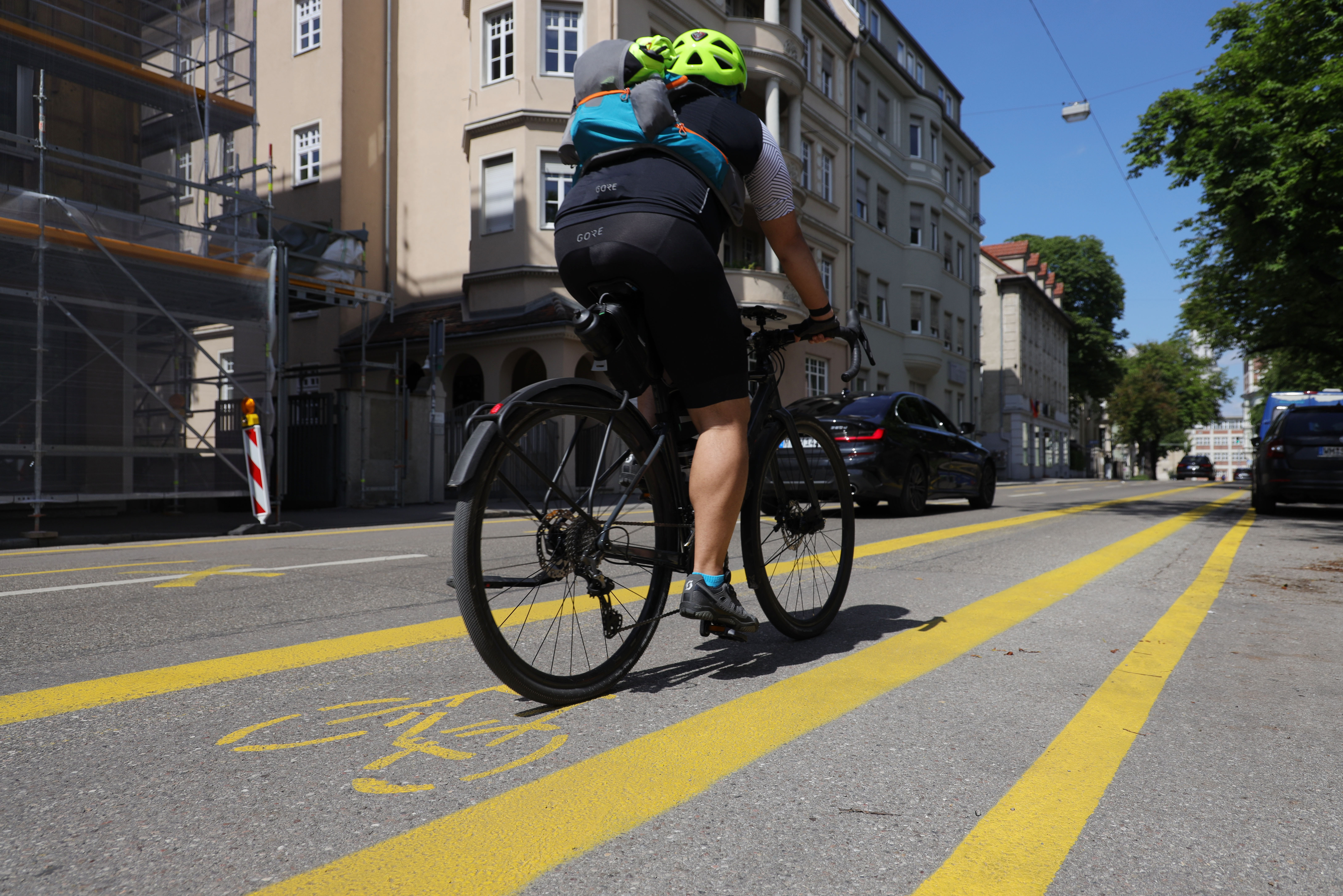 Auf einer Straße in der Innenstadt sind Fahrradstreifen gelb markiert. Ein Radler fährt von links ins Bild.