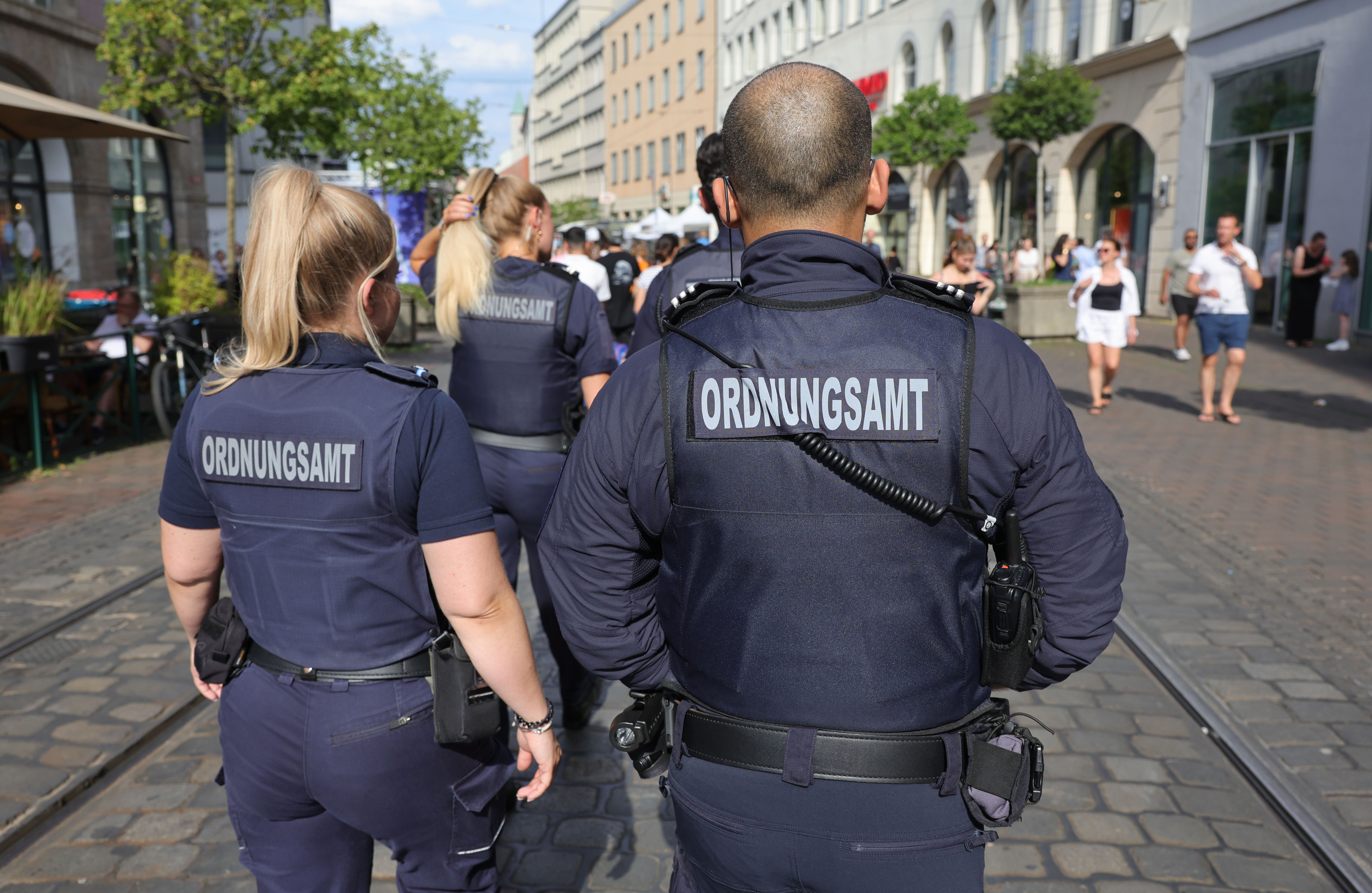 je zwei Männer und Frauen in der Uniform des Ordnungsdienstes, von hinten gesehen