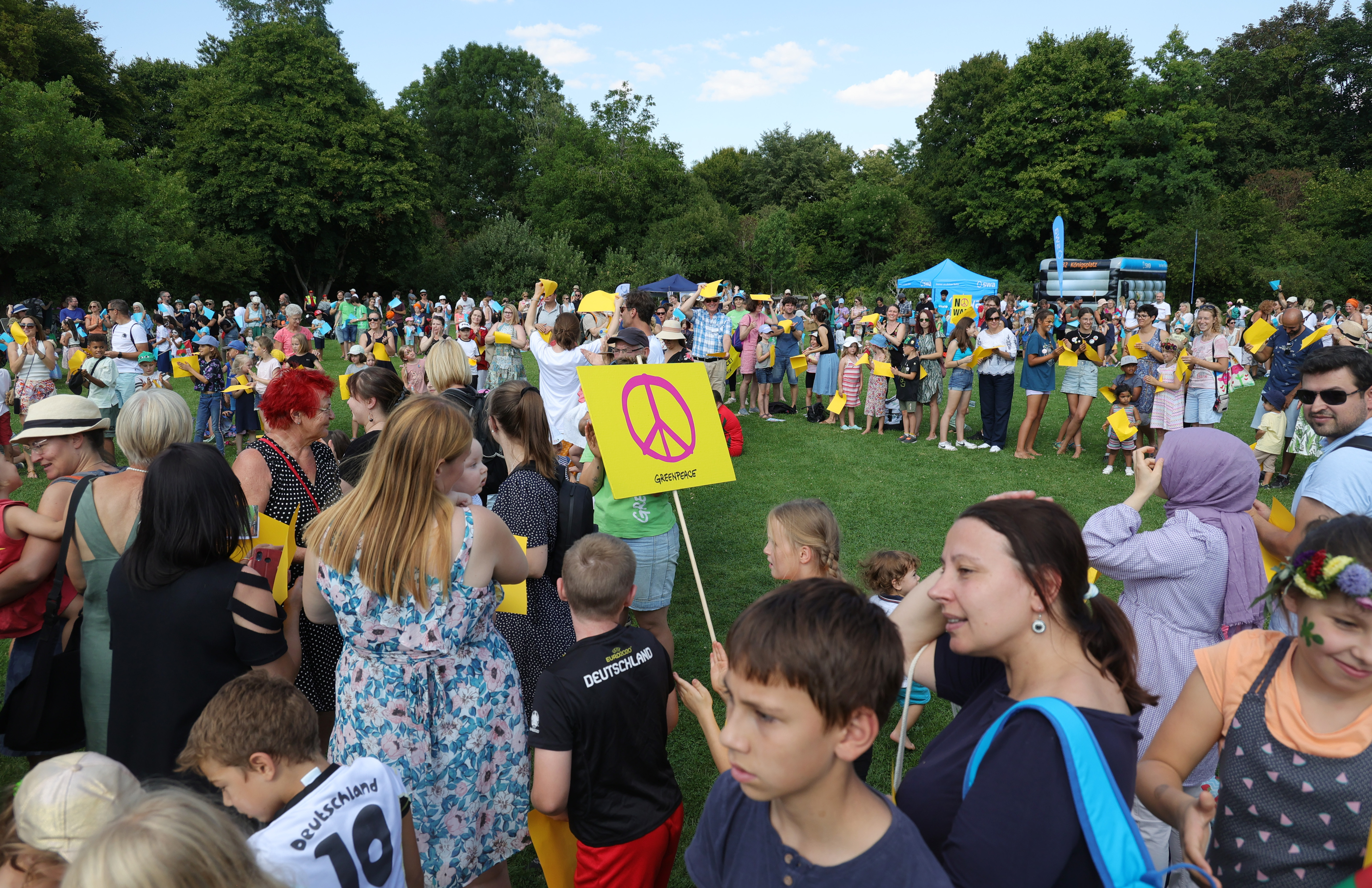 Peace-Zeichen beim Kinderfriedensfest 2022. Foto: Michael Hochgemuth/Stadt Augsburg Hunderte Kinder und Erwachsene stehen im Botanischen Garten
