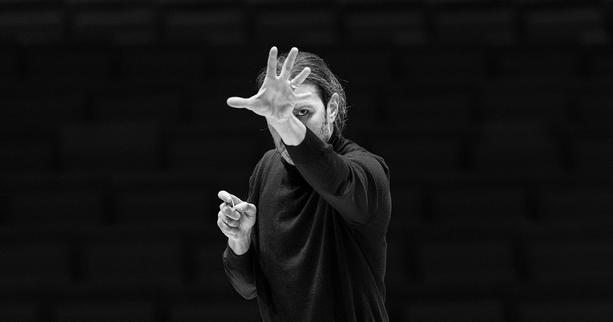 Schwarz-Weiß-Bild eines Dirigenten mit dramatischem Blick. 