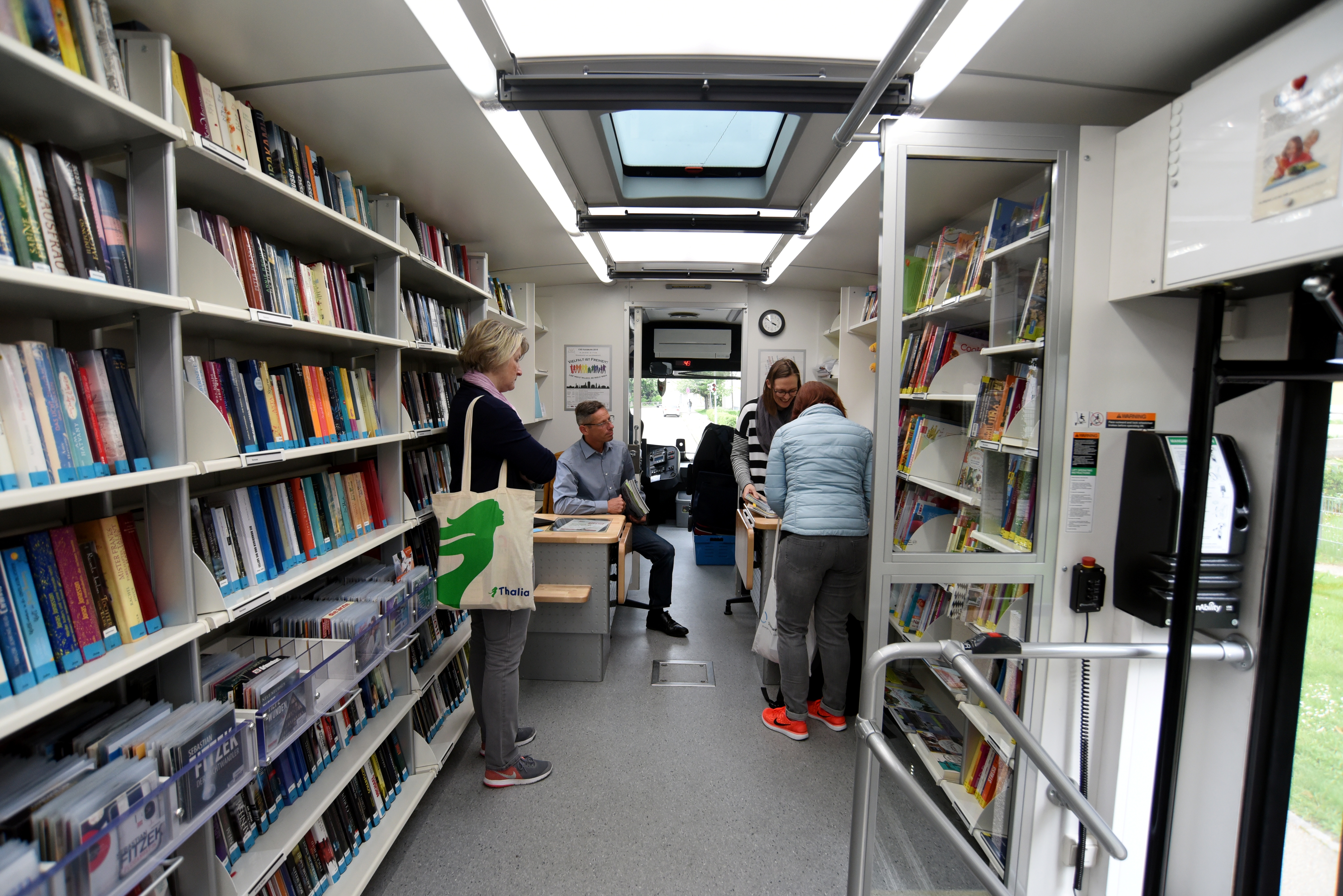 Bücherbus von innen. Vor den Regalen mit Büchern stehen mehrere Leute.