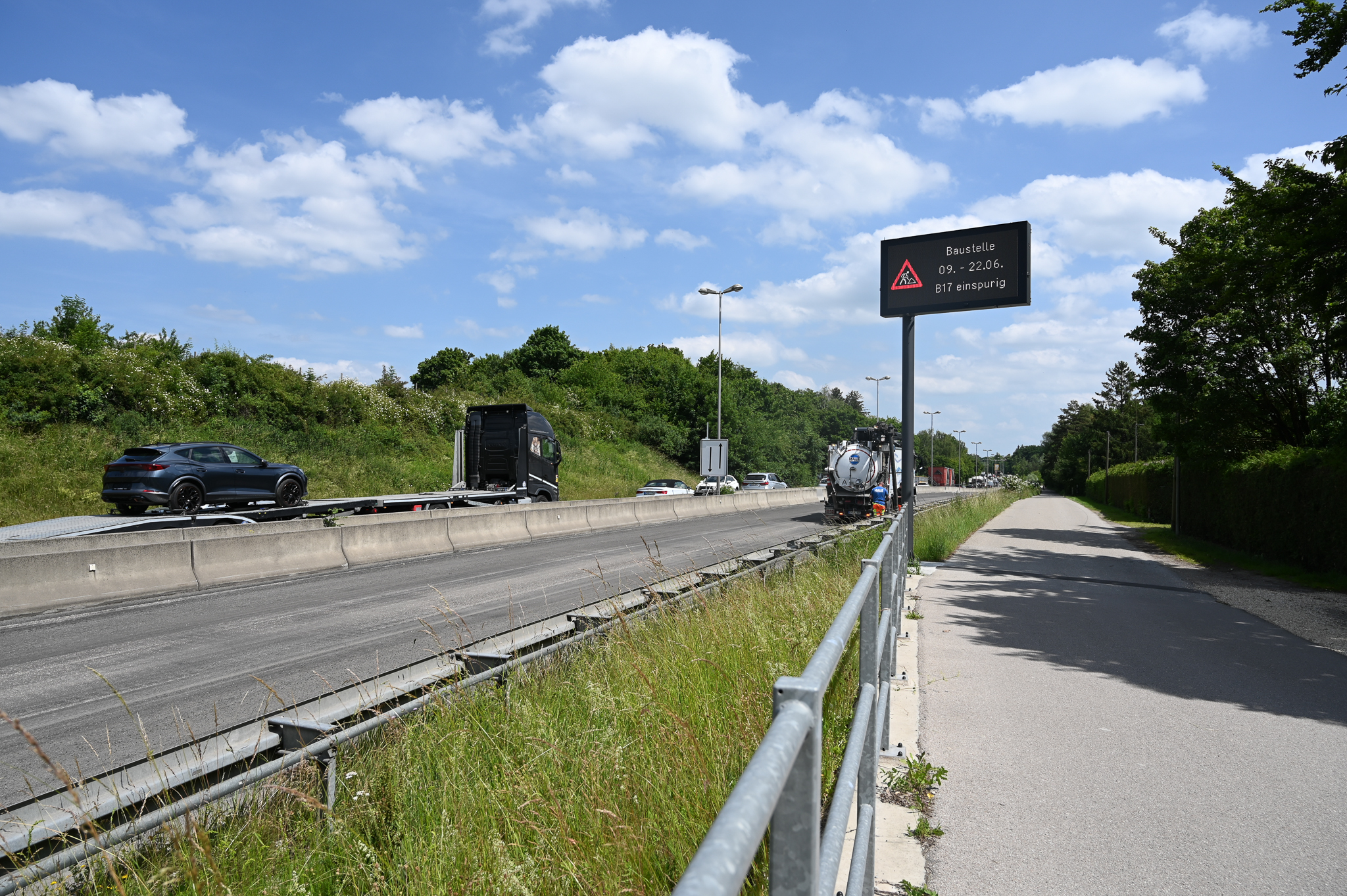 Vierspurige Strasse, an der am rechten Fahrbahnrand eine digitale Verkehrstafel zu sehen ist
