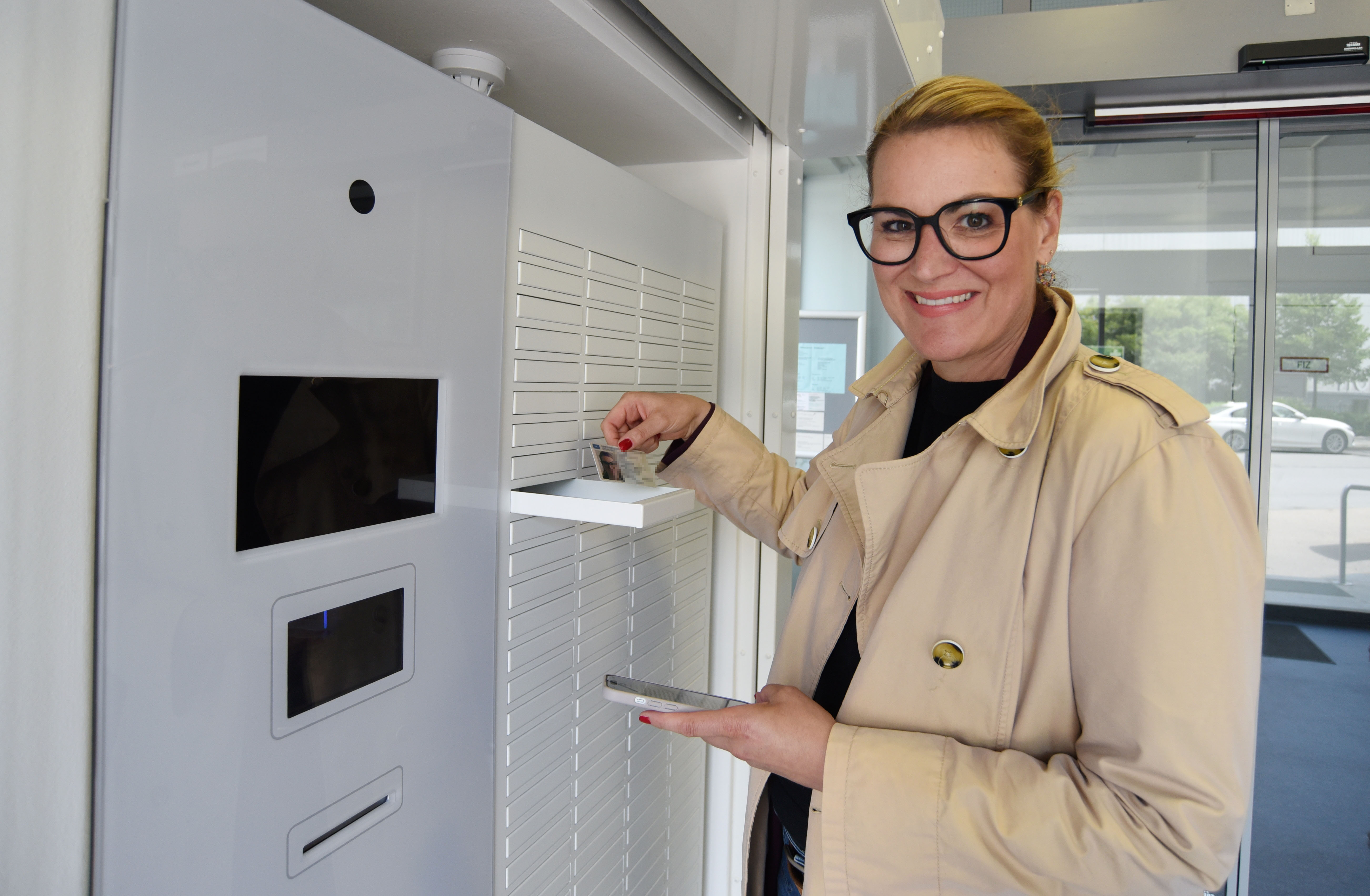 Oberbürgermeisterin Eva Weber steht vor einem Automaten. Eine kleine Schublade ist geöffnet.