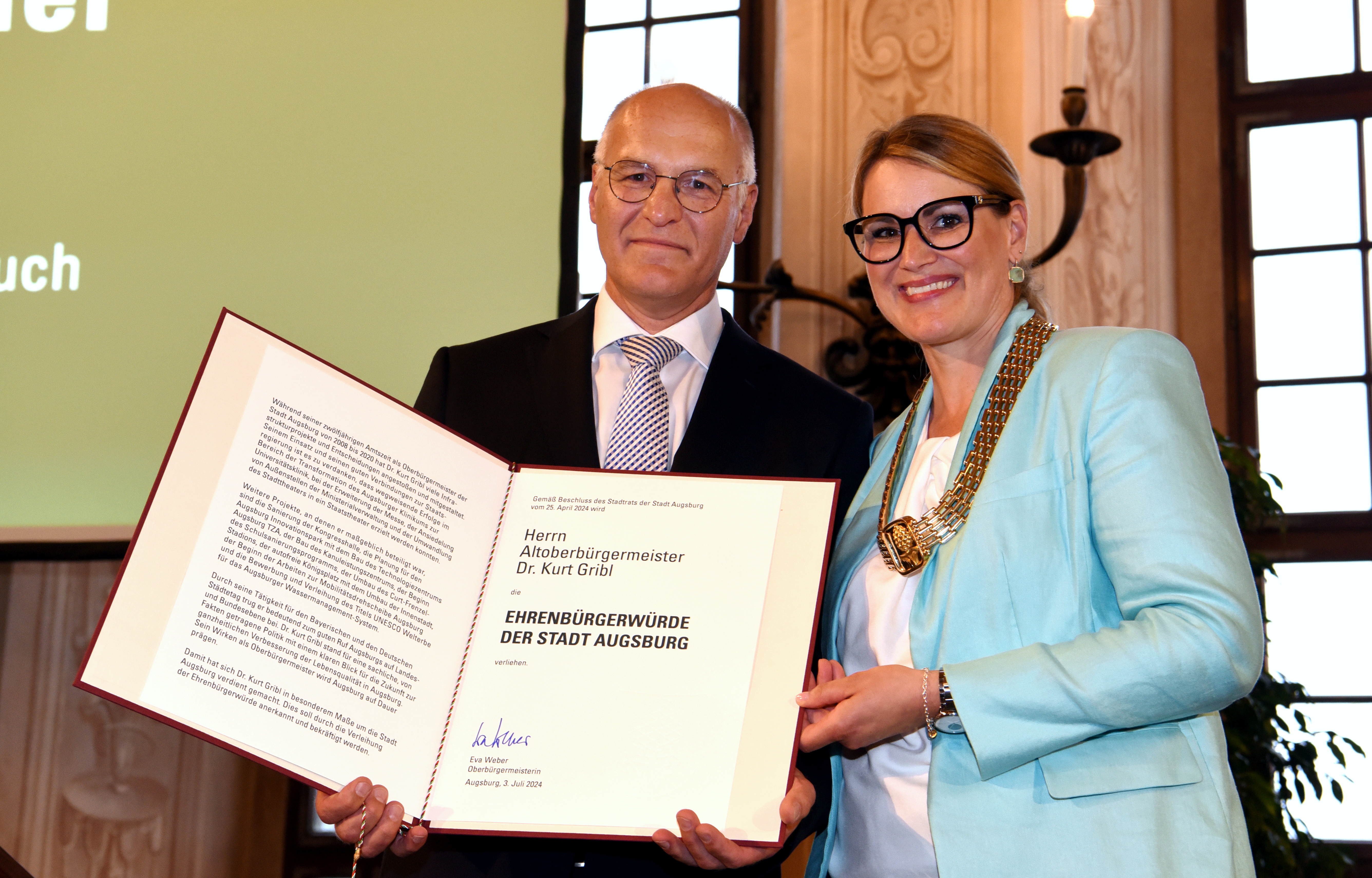 Kurt Gribl hält eine große Urkunde in der Hand, neben ihm OB Eva Weber