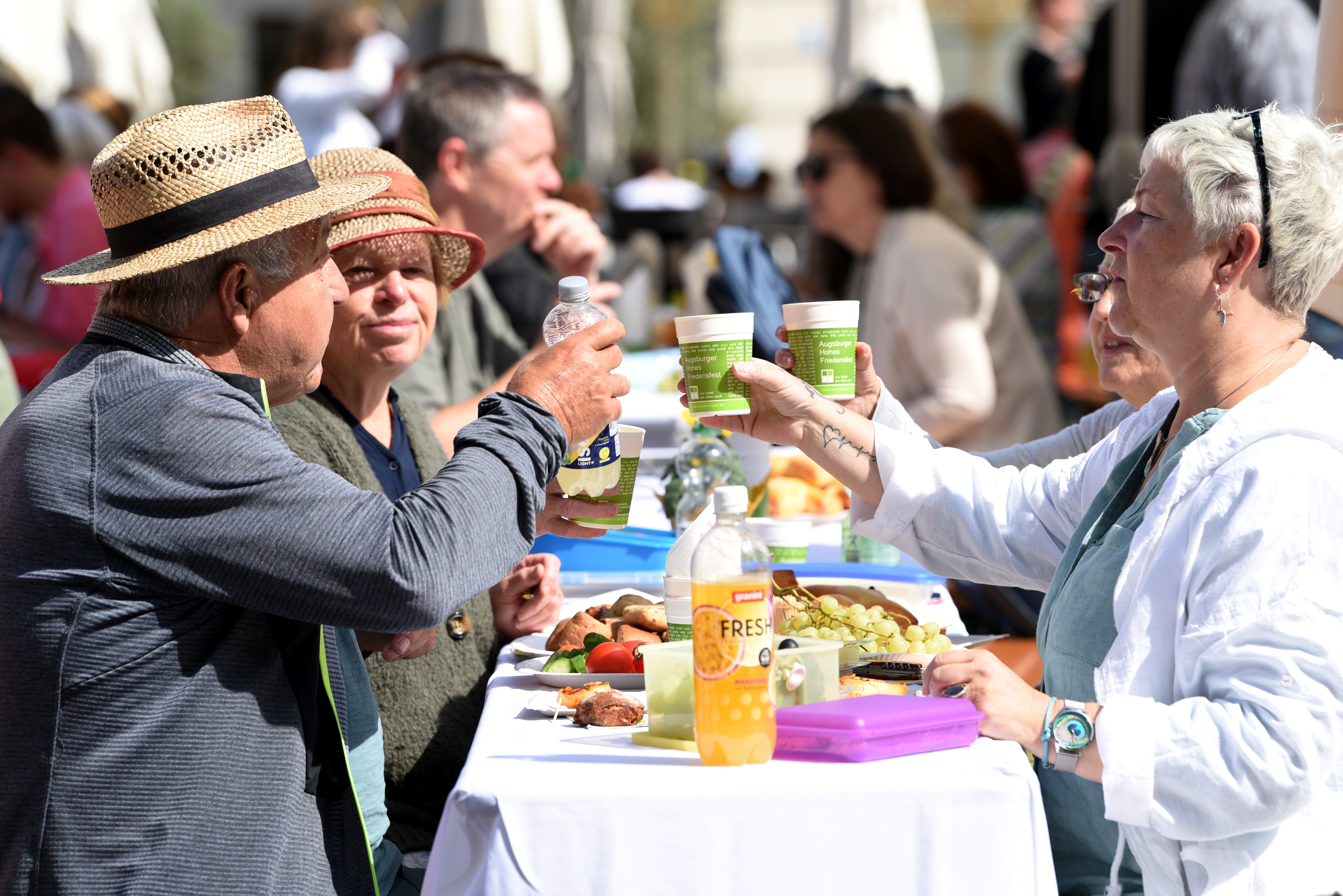 Menschen sitzen an deckten Tischen auf dem Rathausplatz und essen und trinken