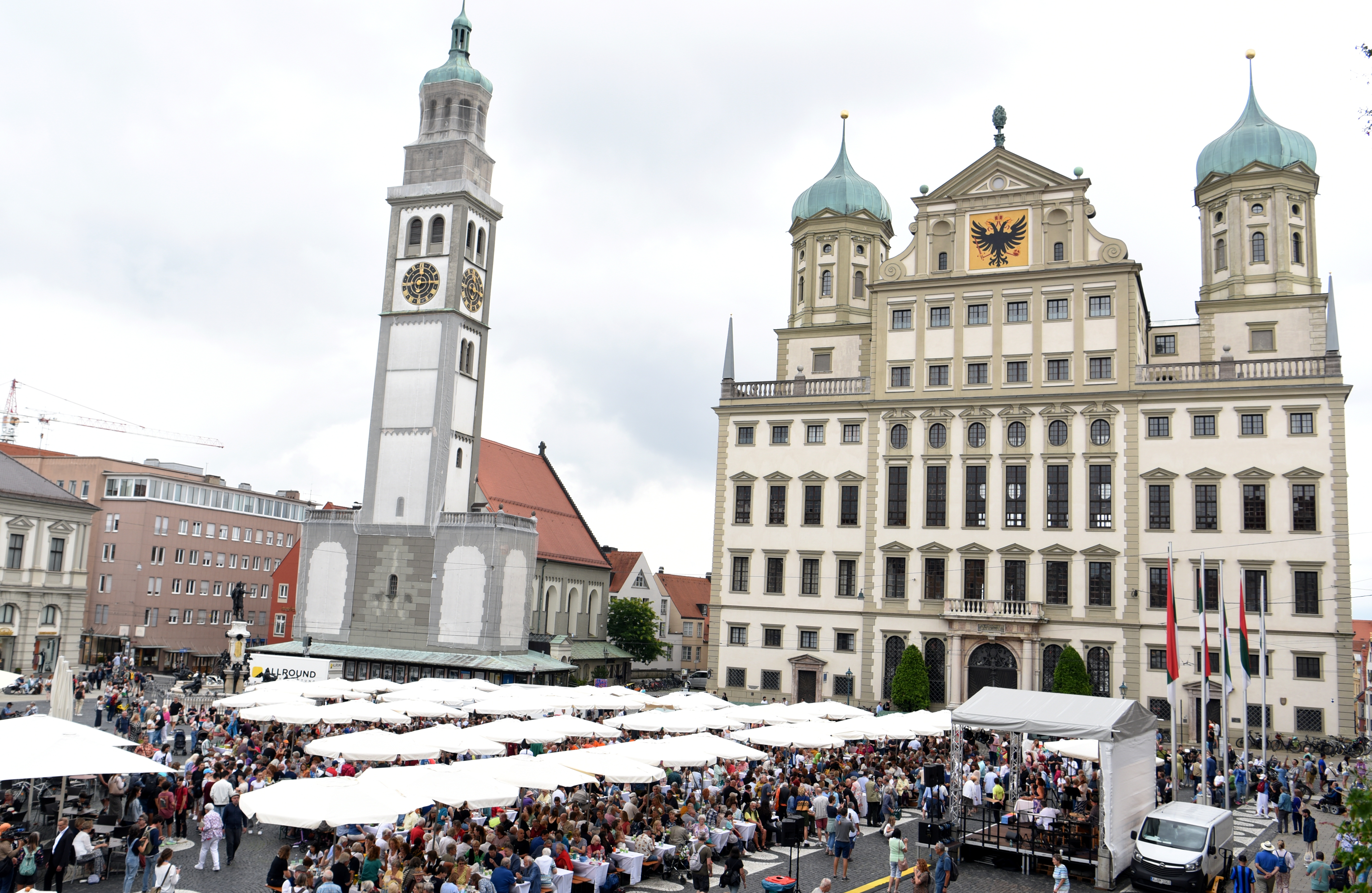 Vor dem Rathaus sitzen rund 1000 Leute an Tischen und essen.