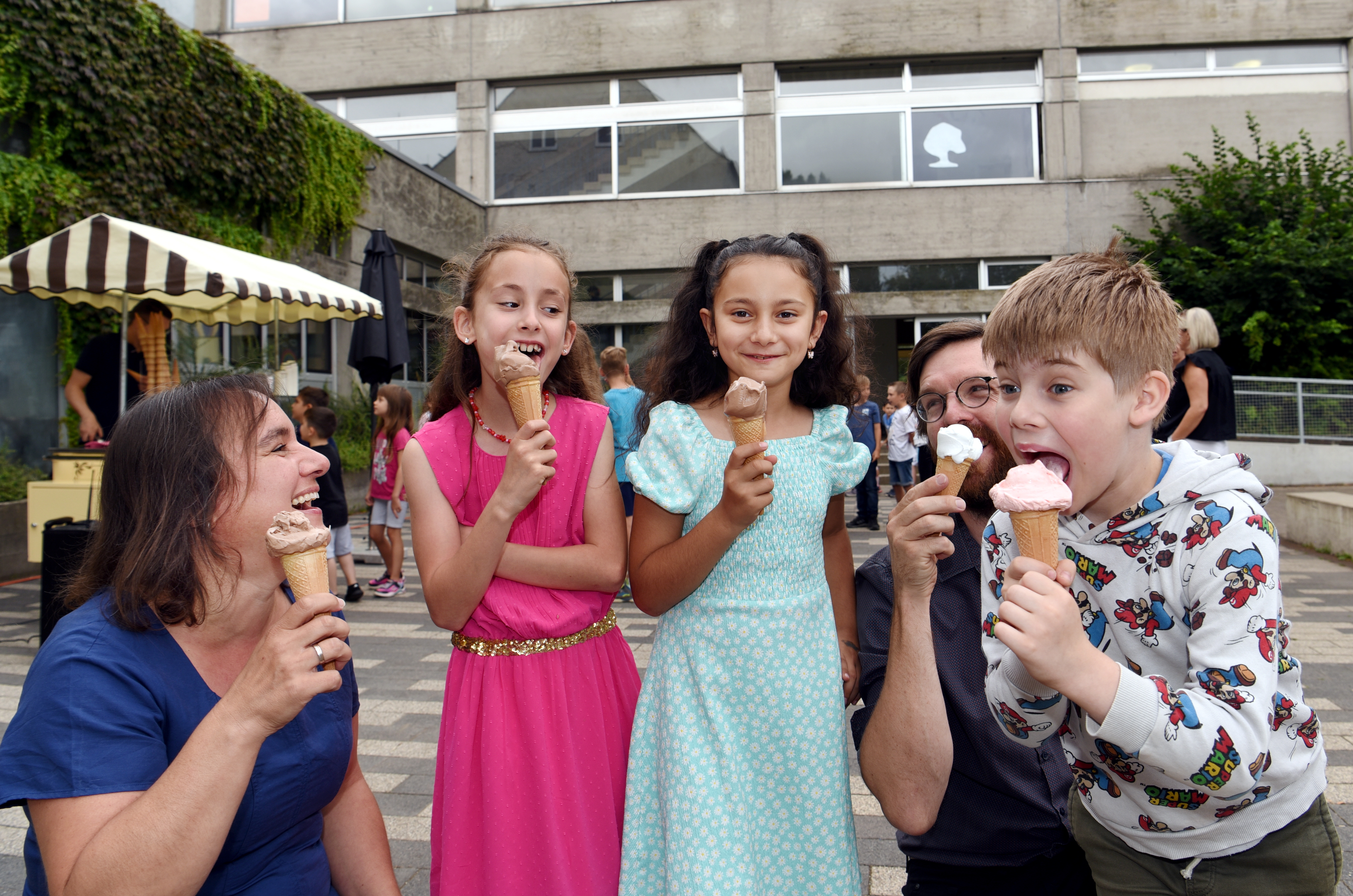 3 Kinder und 2 Erwachsene halten jeweils eine Tüte mit Eis
