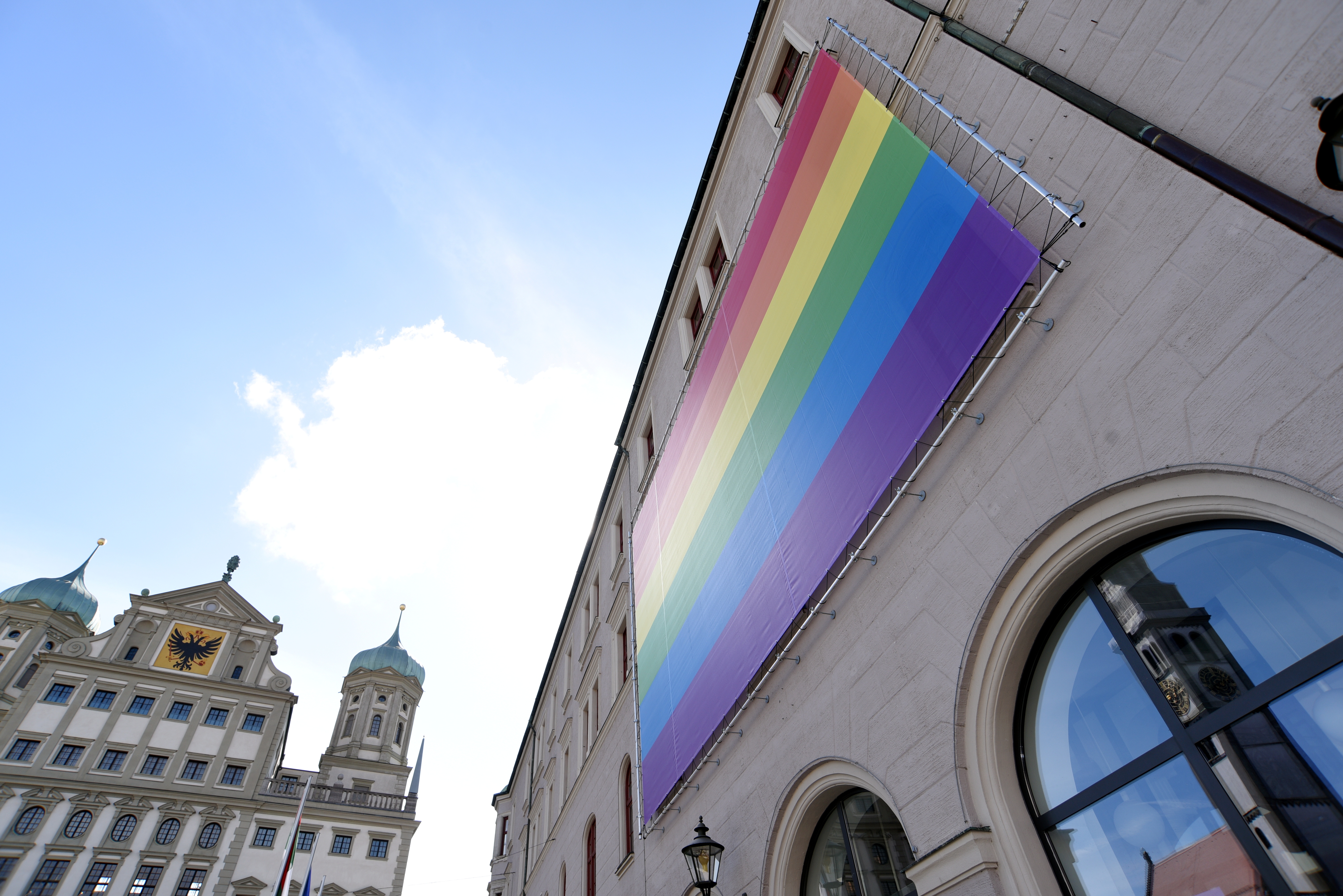 An der Fassade des Verwaltungsgebäudes am Rathausplatz hängt ein großer Regenbogen-Banner