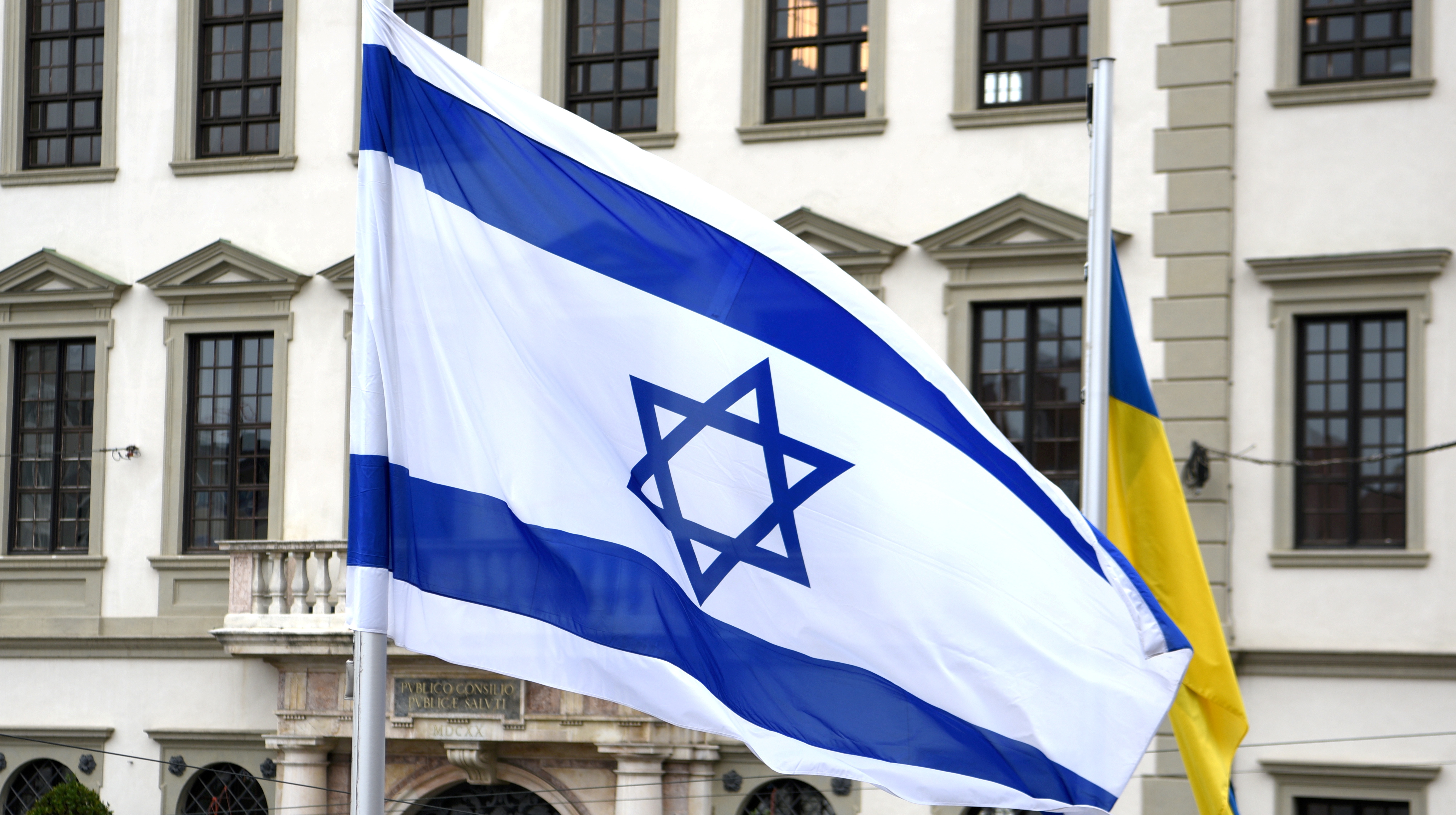 Man sieht die Flagge von Israel vor einem Gebäude wehen.