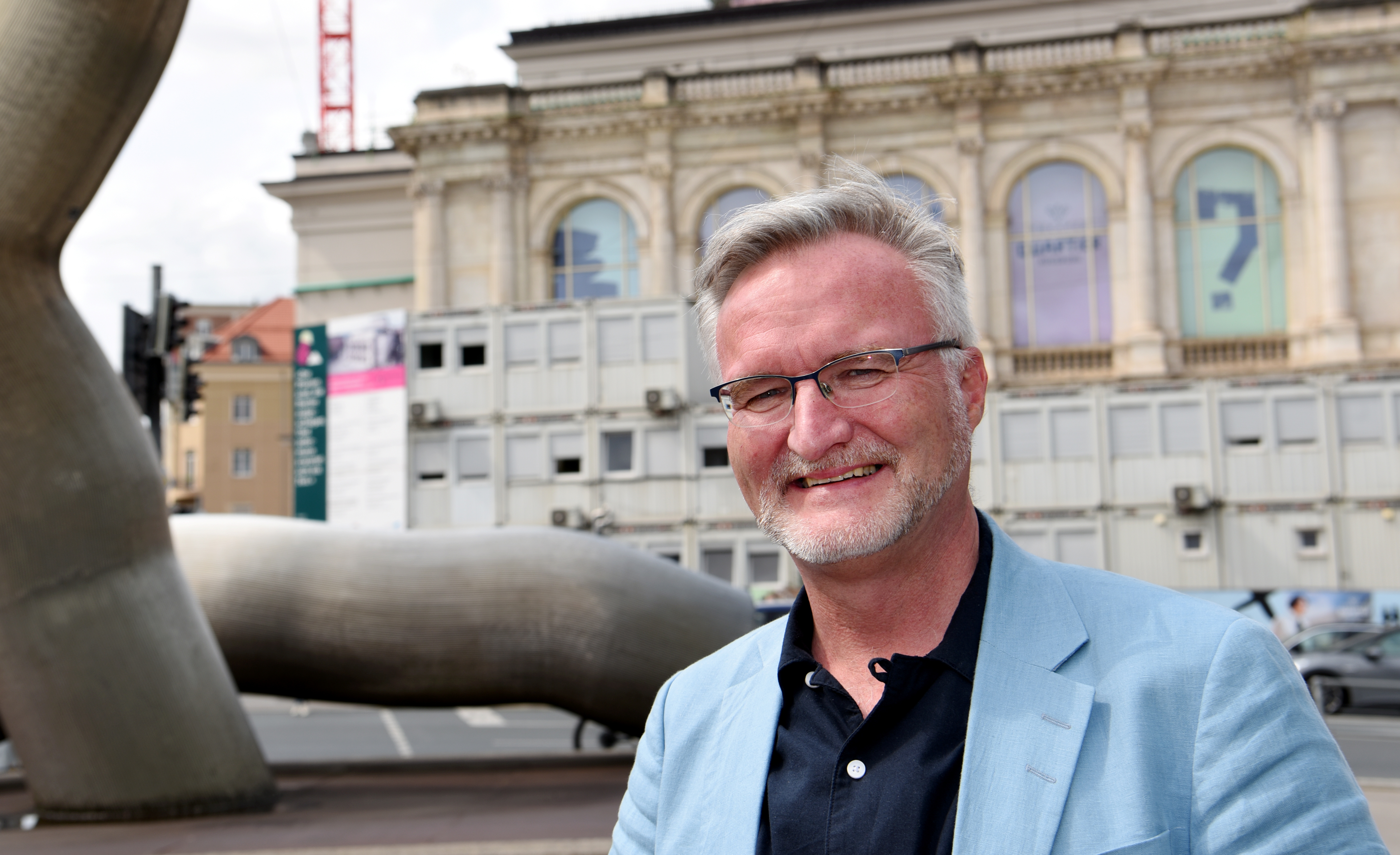 Ein Mann mit blauem Sakko steht vor dem Staatstheater