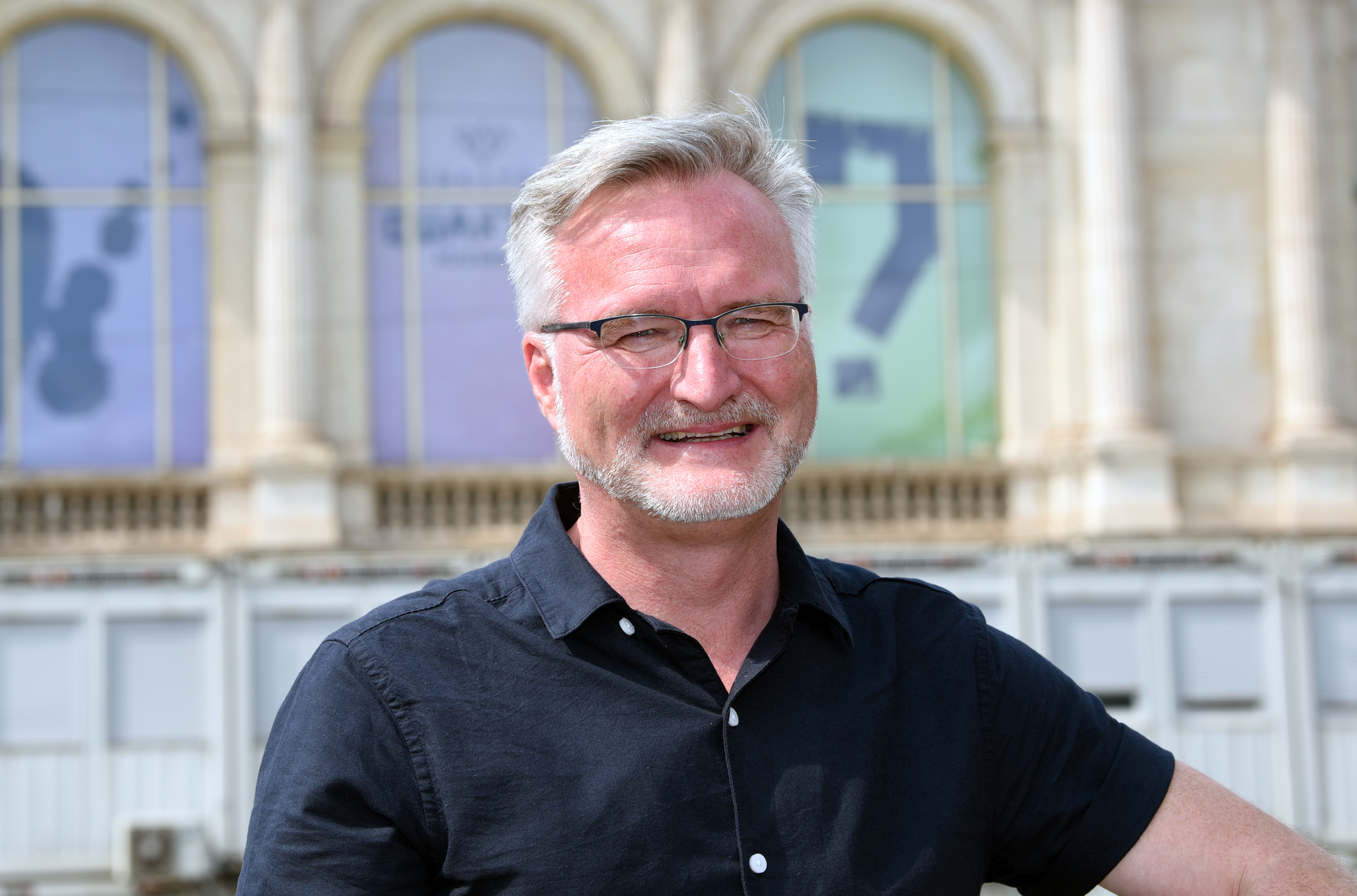 Jürgen Enninger steht im schwarzen kurzärmligen Hemd vor dem Staatstheater