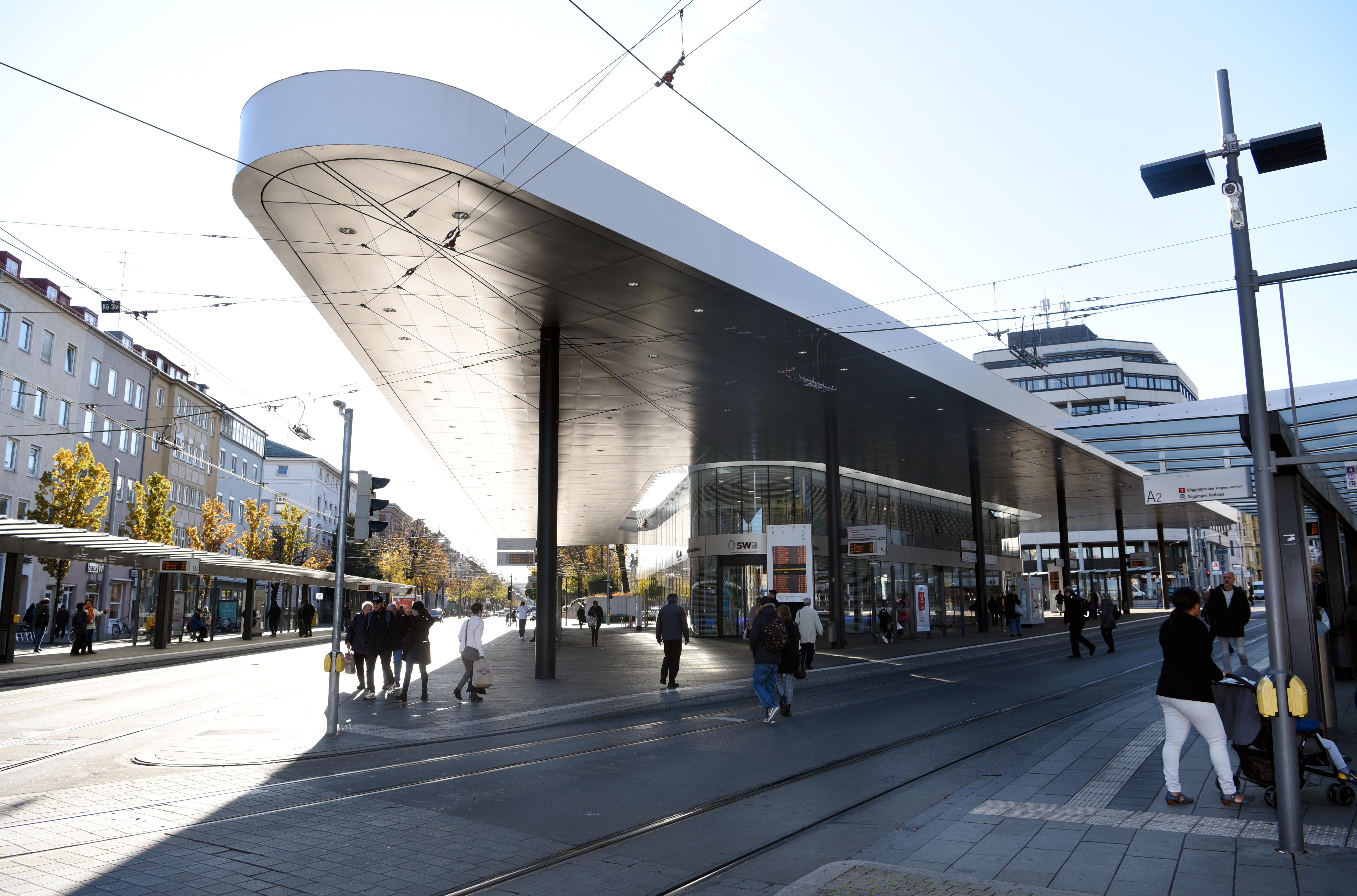 Das Haltestellen-Dreieck am Königsplatz. Es sind keine Busse oder Straßenbahnen zu sehen. Nur ein paar Leute stehen an den Haltestellen.