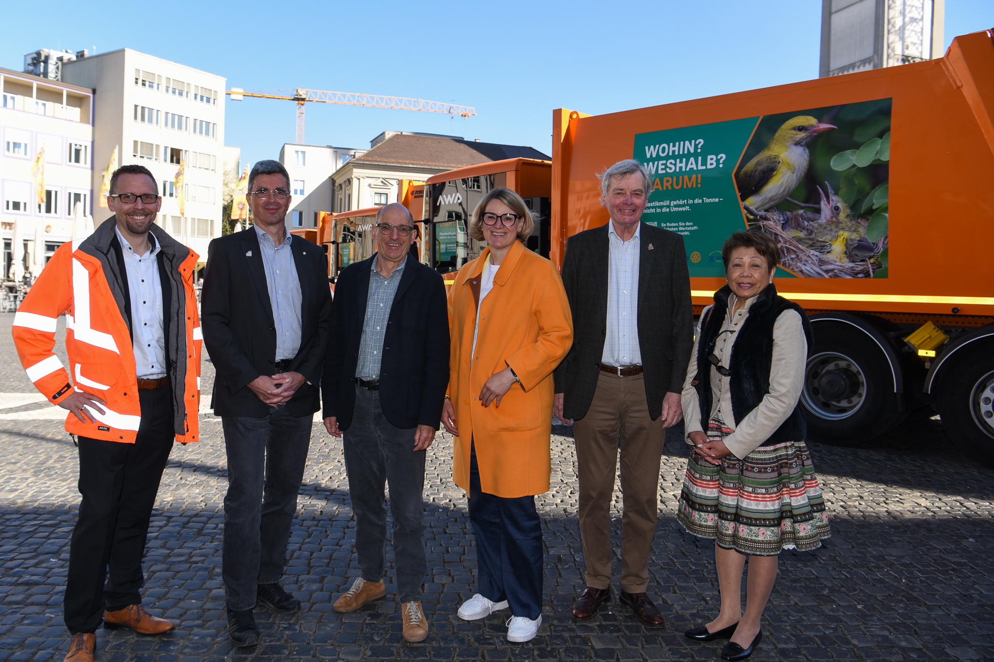 Fünf Menschen stehen vor einem Müllauto. Auf dem Fahrzeug ist ein großes Foto von einem Vogelnest, das zum Teil aus Plastik besteht
