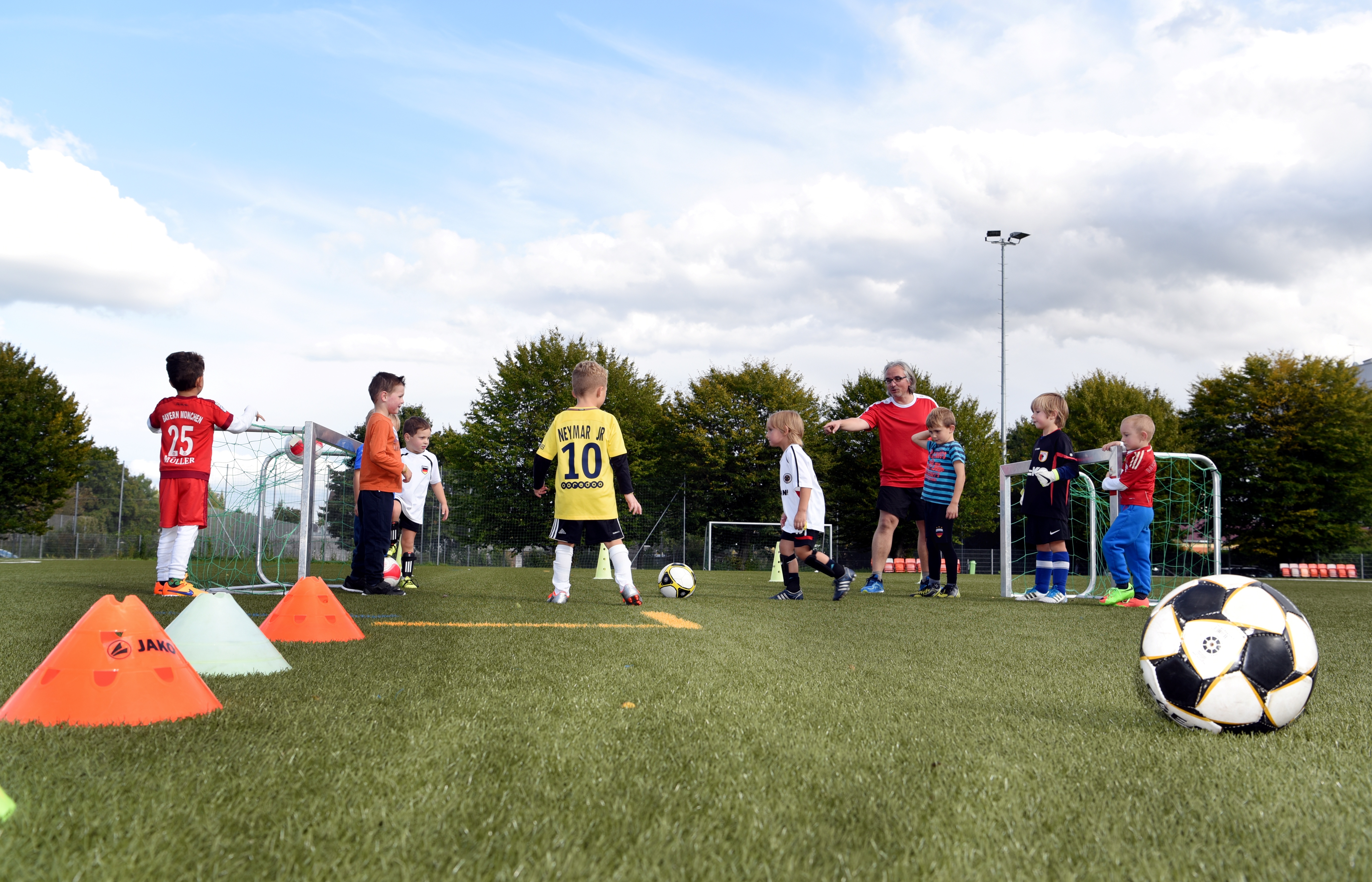 Kinder spielen Fußball. Ein Trainer gibt Anweisungen