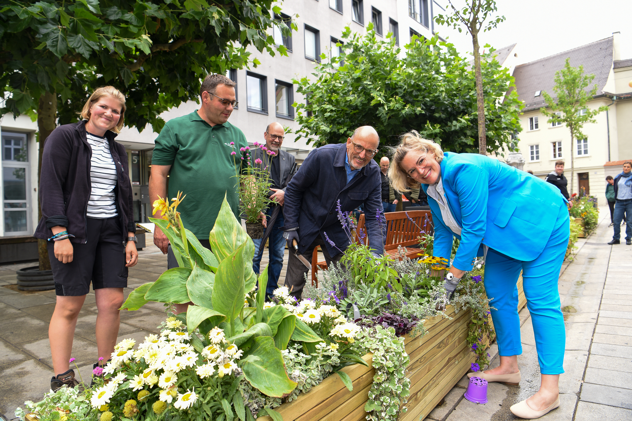 Einige Leute planzen Blumen in Holzkästen mitten in der Stadt