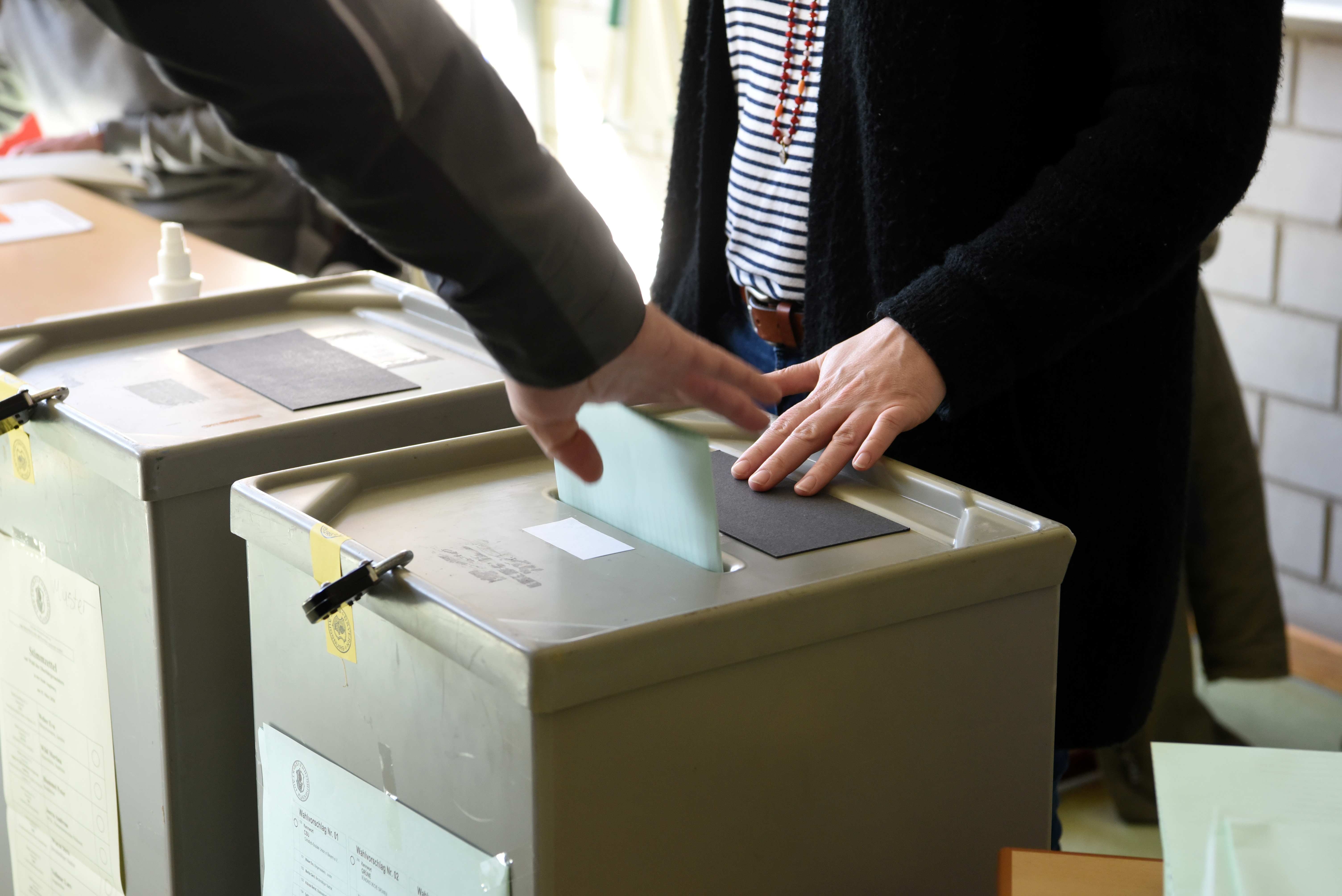 Ein Wahlzettel wird in die Wahlurne gesteckt. 
