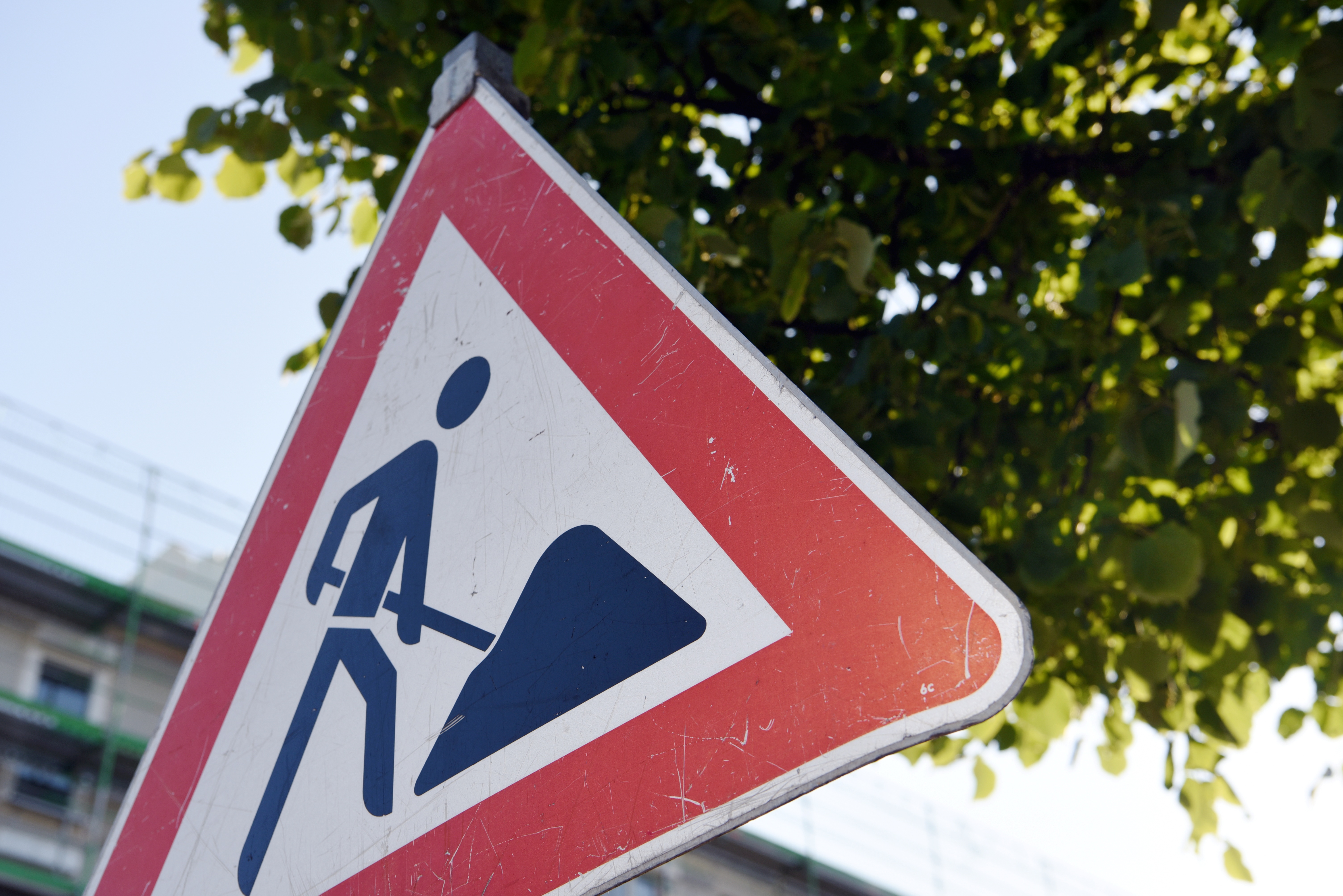 Baustellenschild vor Baum und Haus