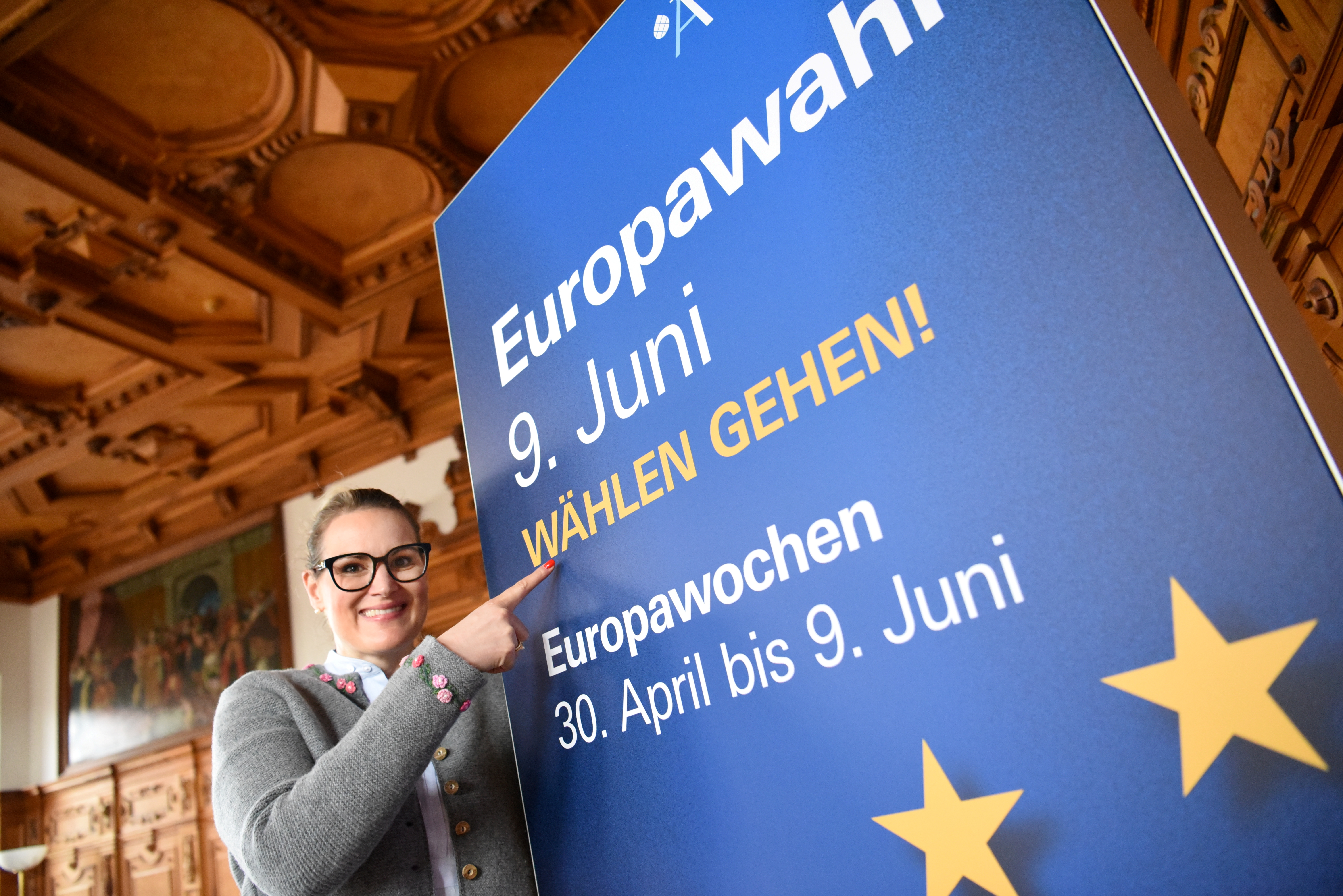 OB Eva Weber zeigt auf ein Plakat, auf dem steht: "Europawahl 9. Juni, Wählen gehen! Europawochen 30. April bis 9. Juni
