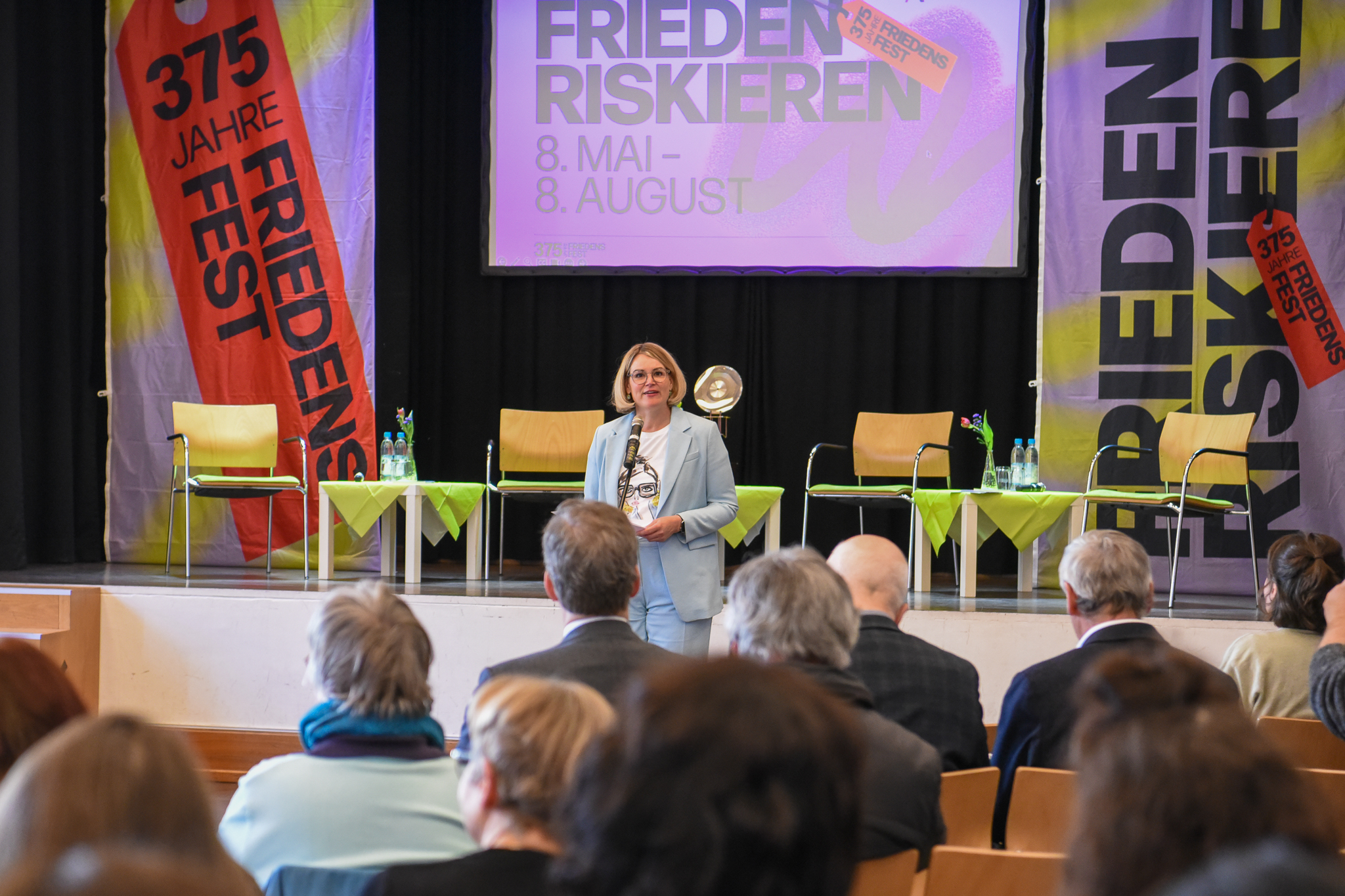 Oberbürgermeisterin Eva Weber spricht vor mehreren Leuten in einem Saal