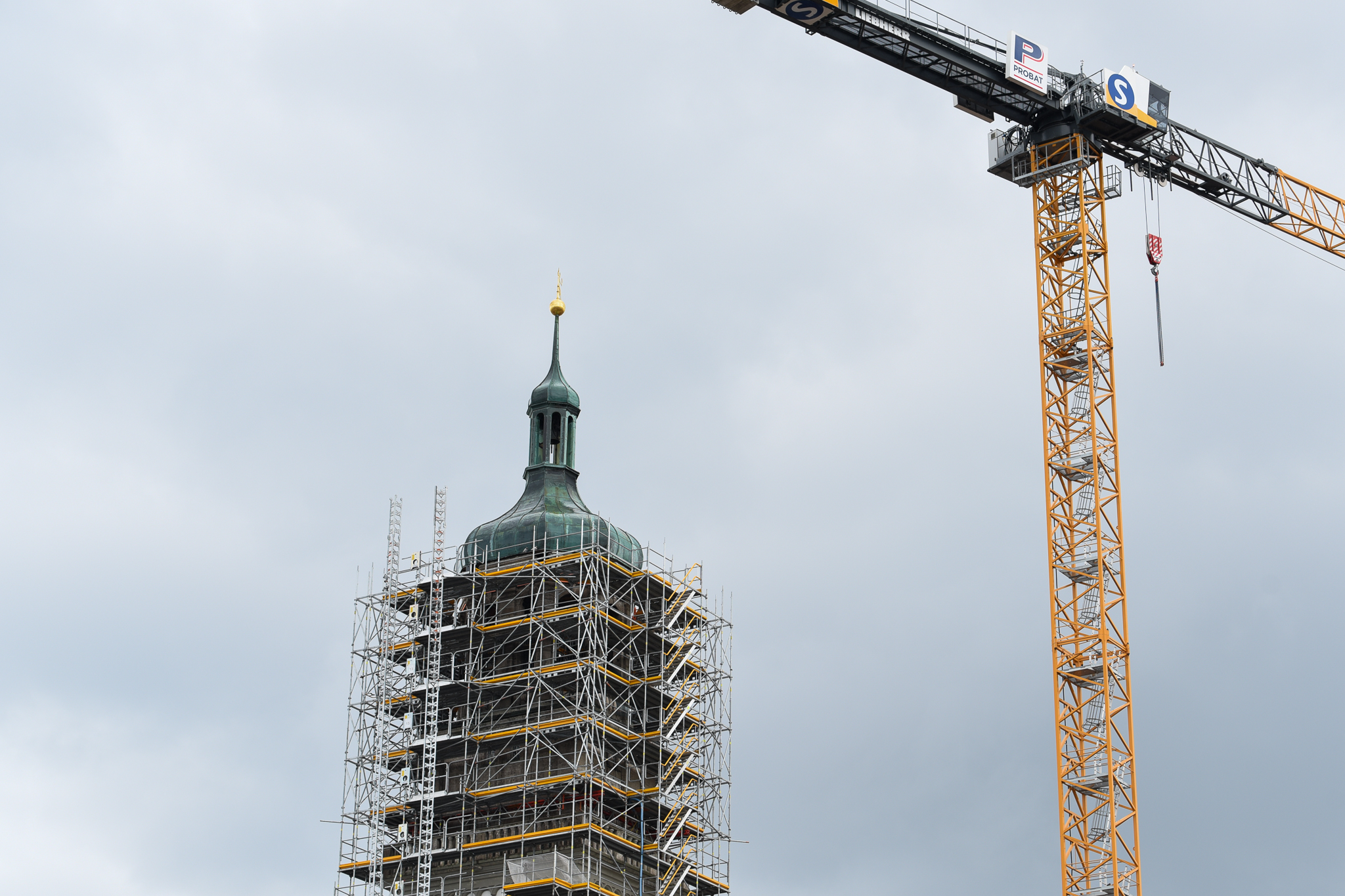 Die Spitze des Perlachturms mit Baugerüst. Daneben steht ein großer Kran
