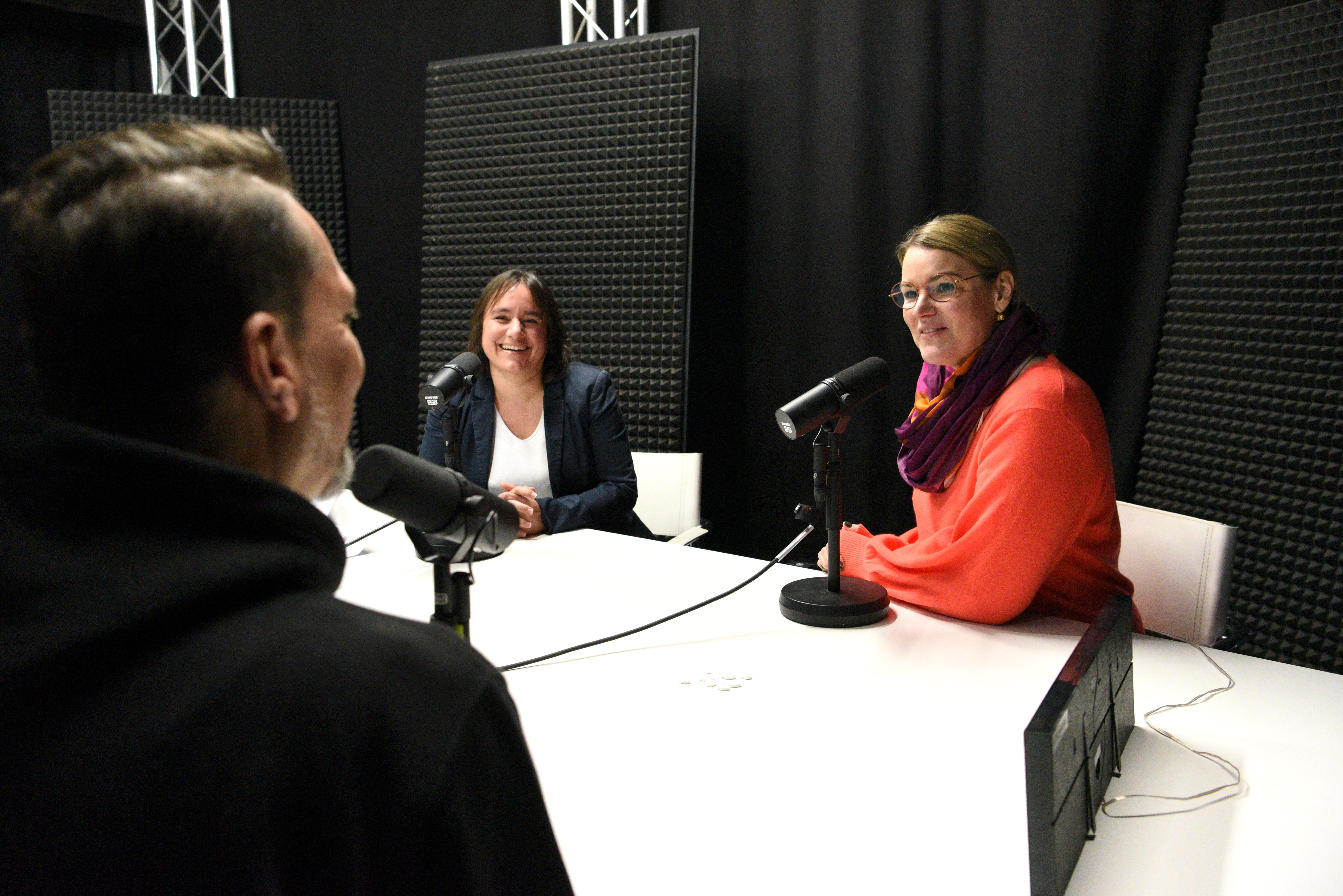 Journalist Markus Krapf, Bürgermeisterin Martina Wild und Oberbürgermeisterin Eva Weber sitzen an einem Tisch in einem Tonstudio. Auf dem Tisch sind Mikrofone aufgestellt. 