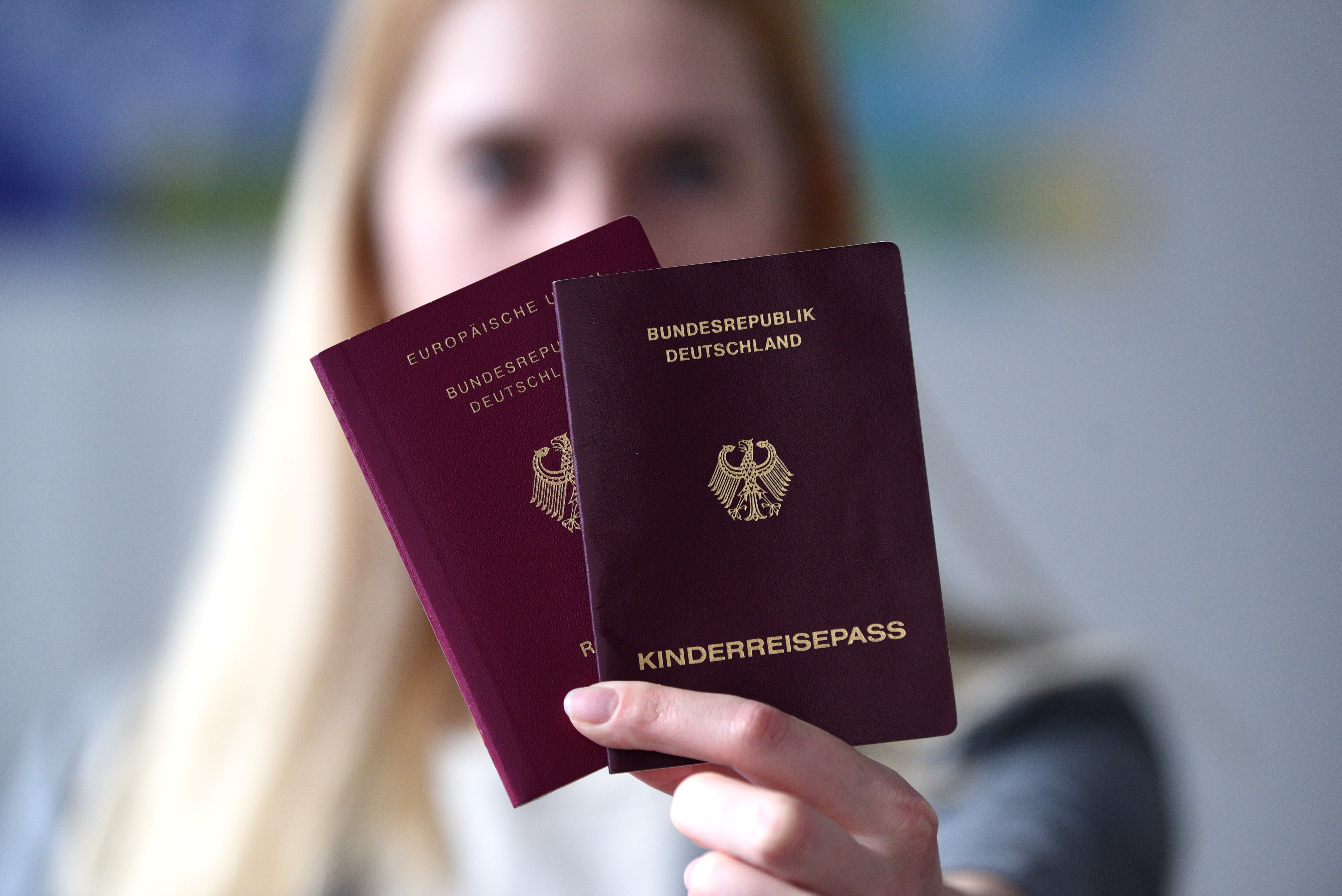 Eine junge Frau hält einen Reisepass und einen Kinderreisepass in die Kamera
