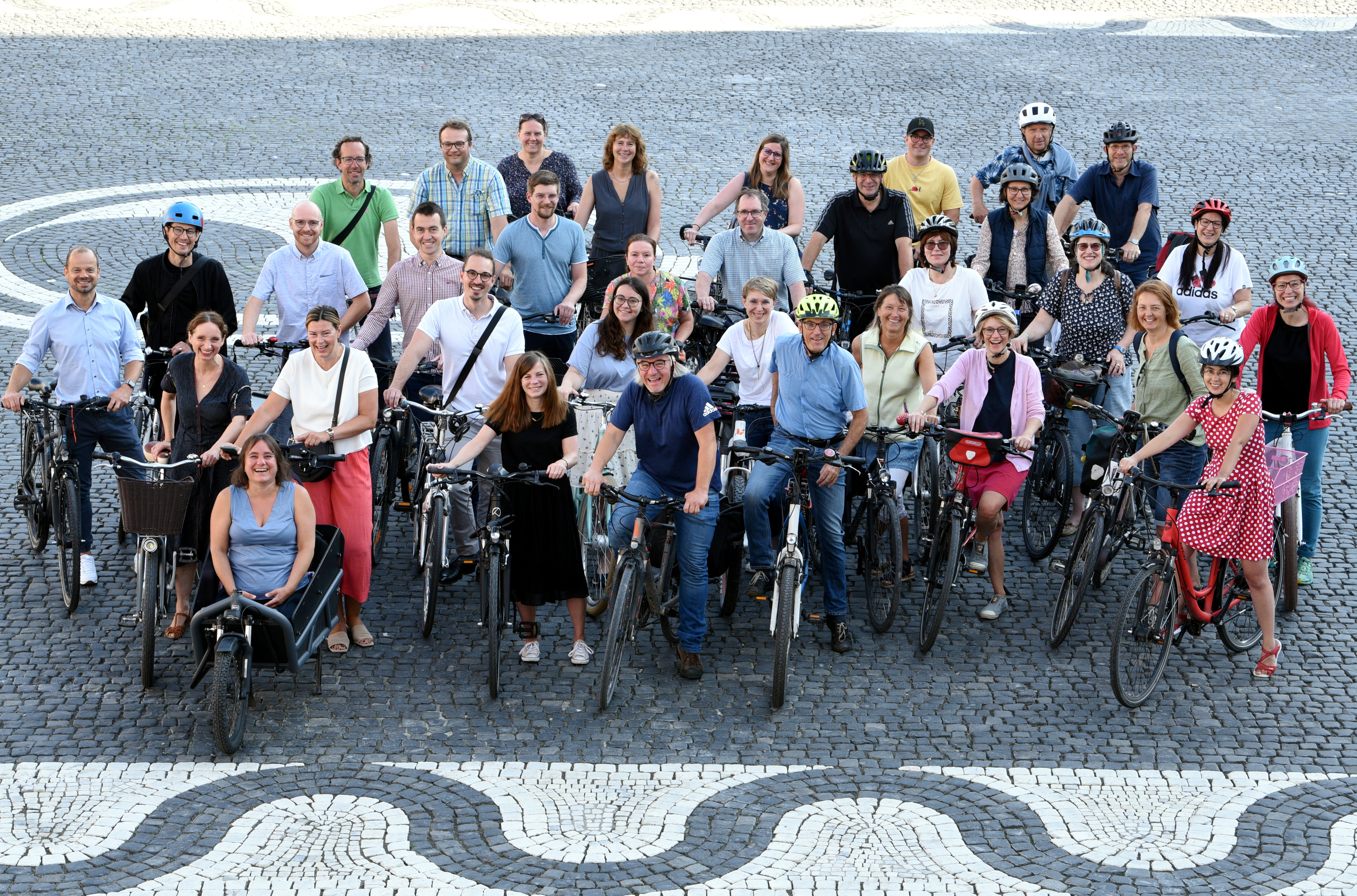 Etwa 35 Frauen und Männer auf Fahrrädern stehen auf dem Rathausplatz zusammen.