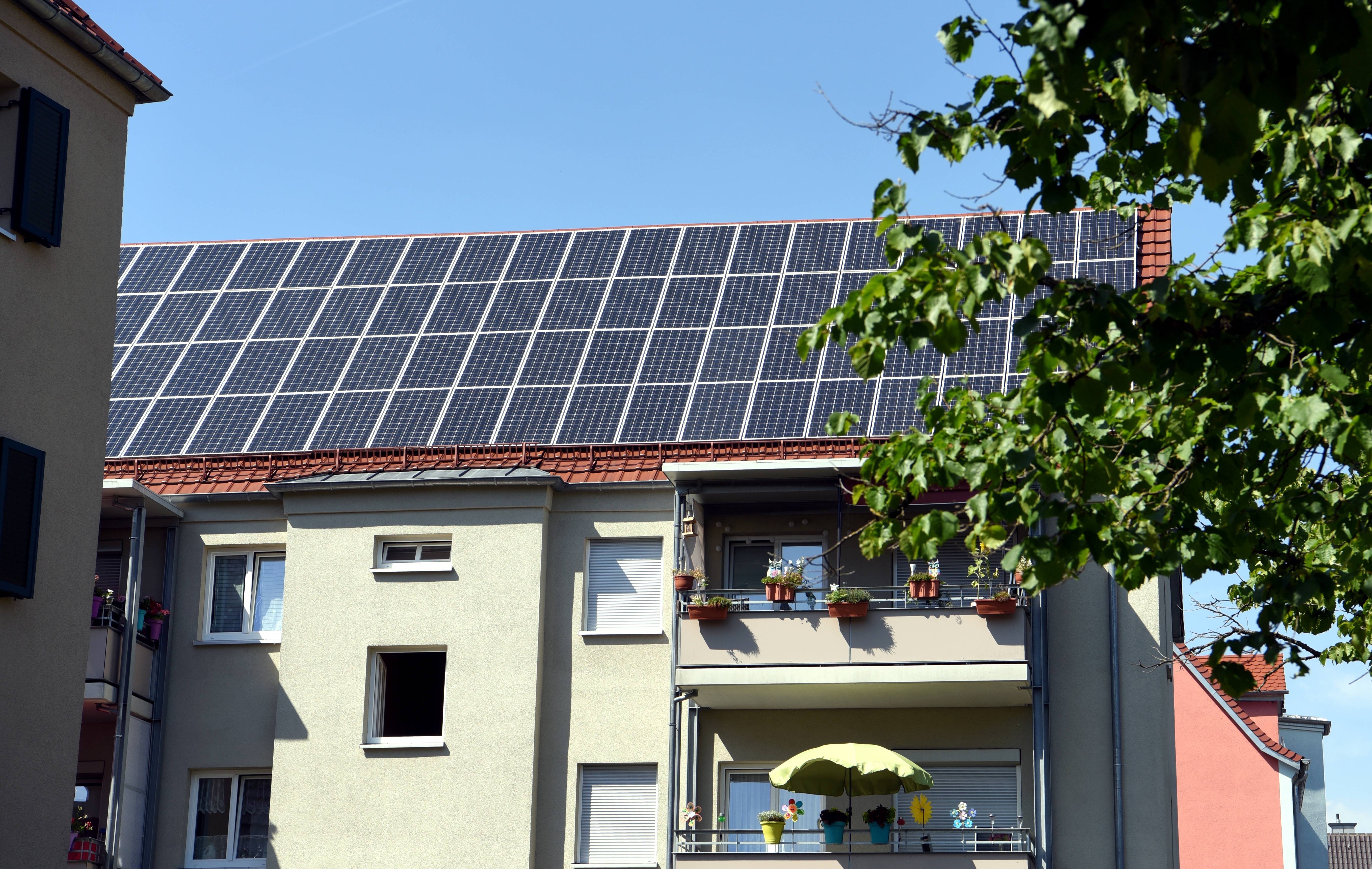 mehrstöckiges Haus mit Balkon; das Dach ist komplett mit Solar-Panels bedeckt