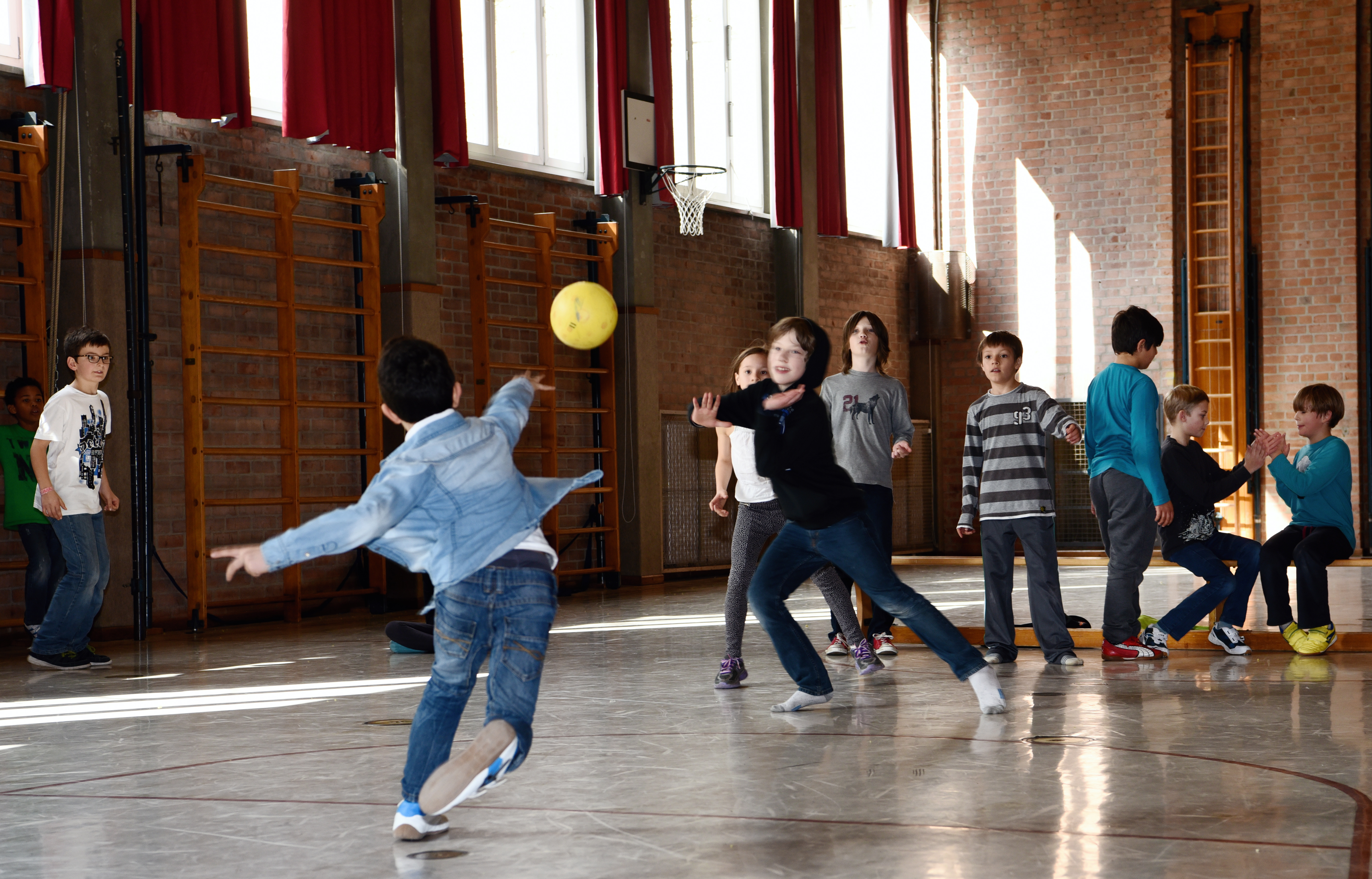 Kinder in Turnhalle werfen Ball