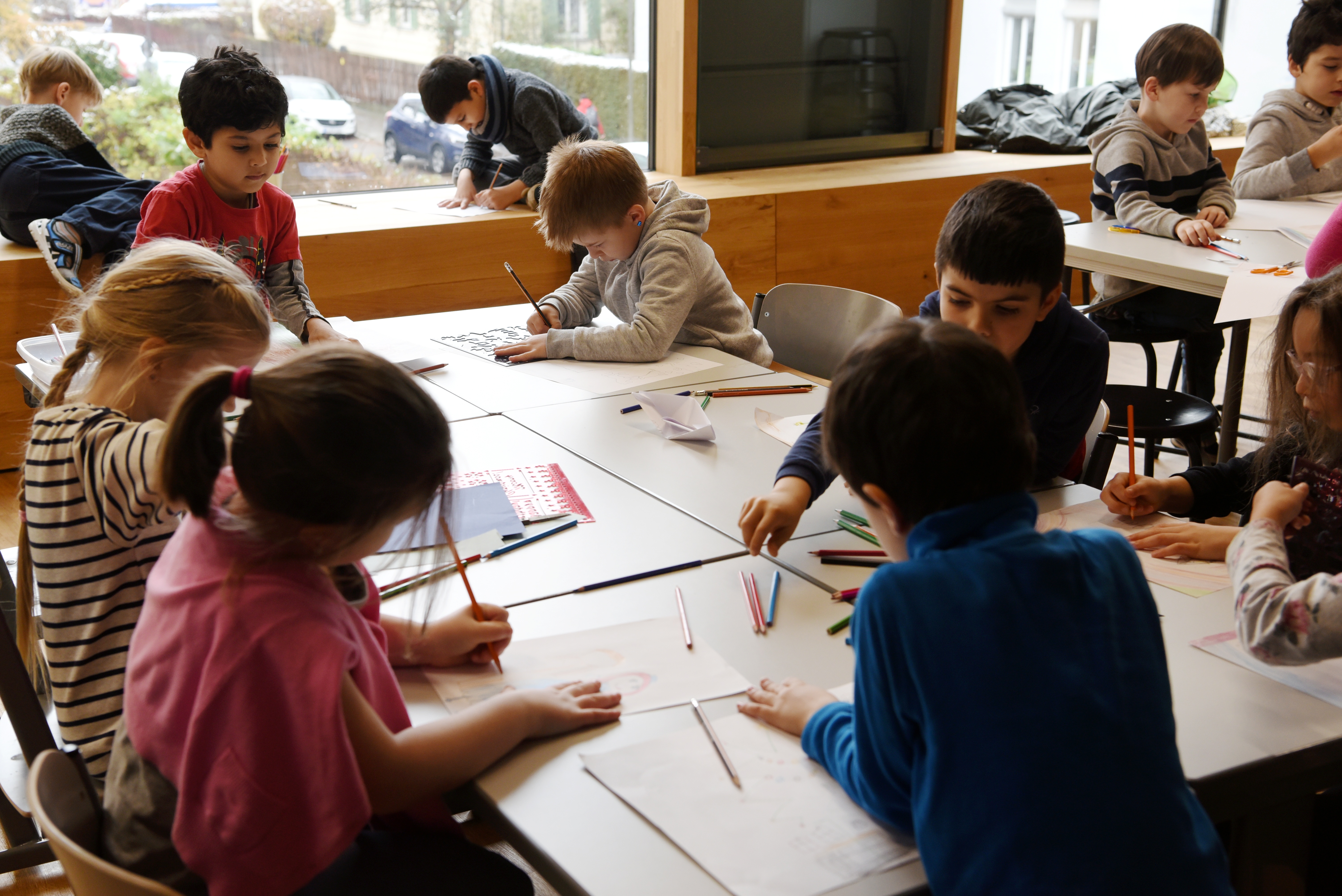 Kinder malen an einem großen Tisch