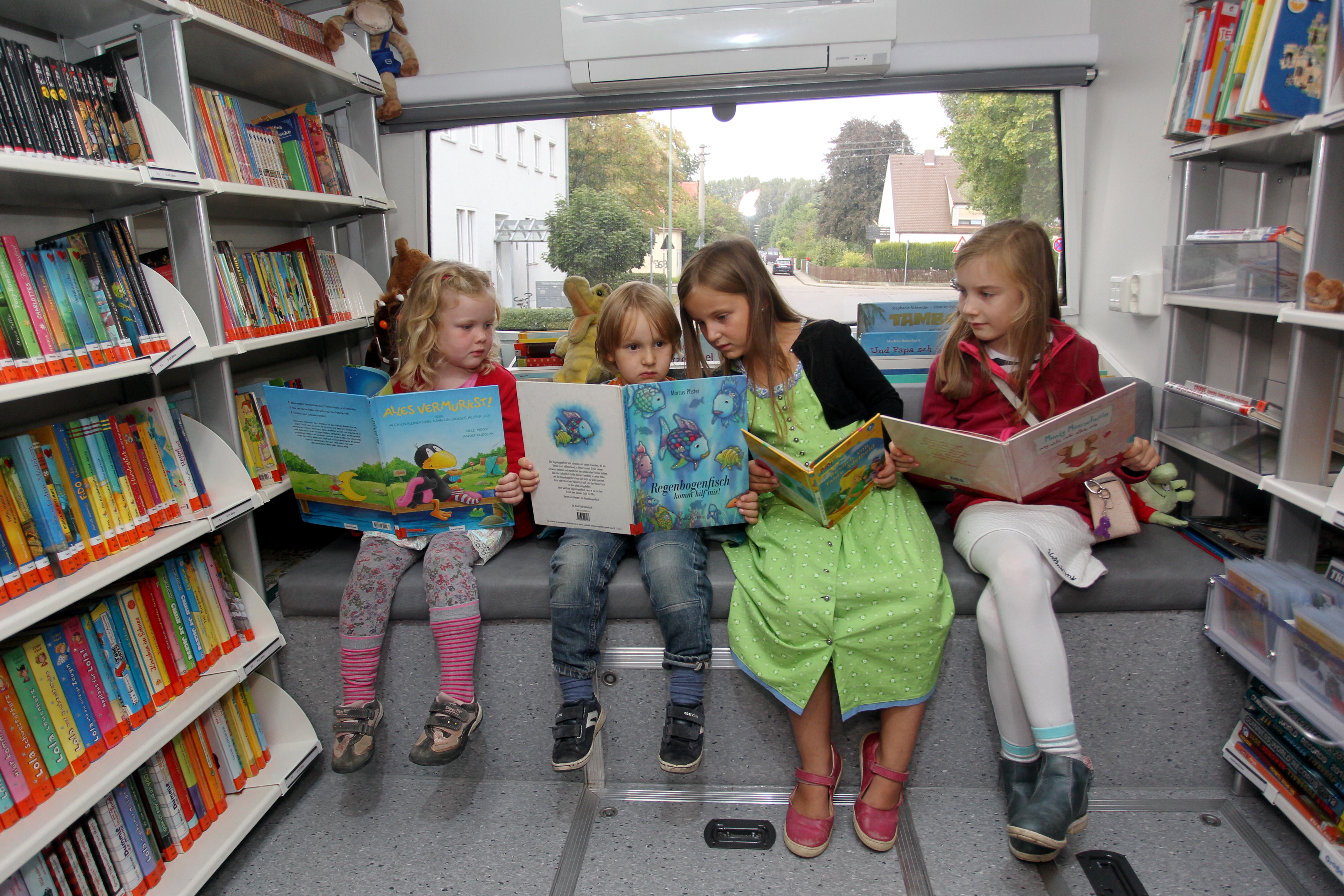 Kinder, die zusammen auf einer Bank sitzen und Bücher lesen.