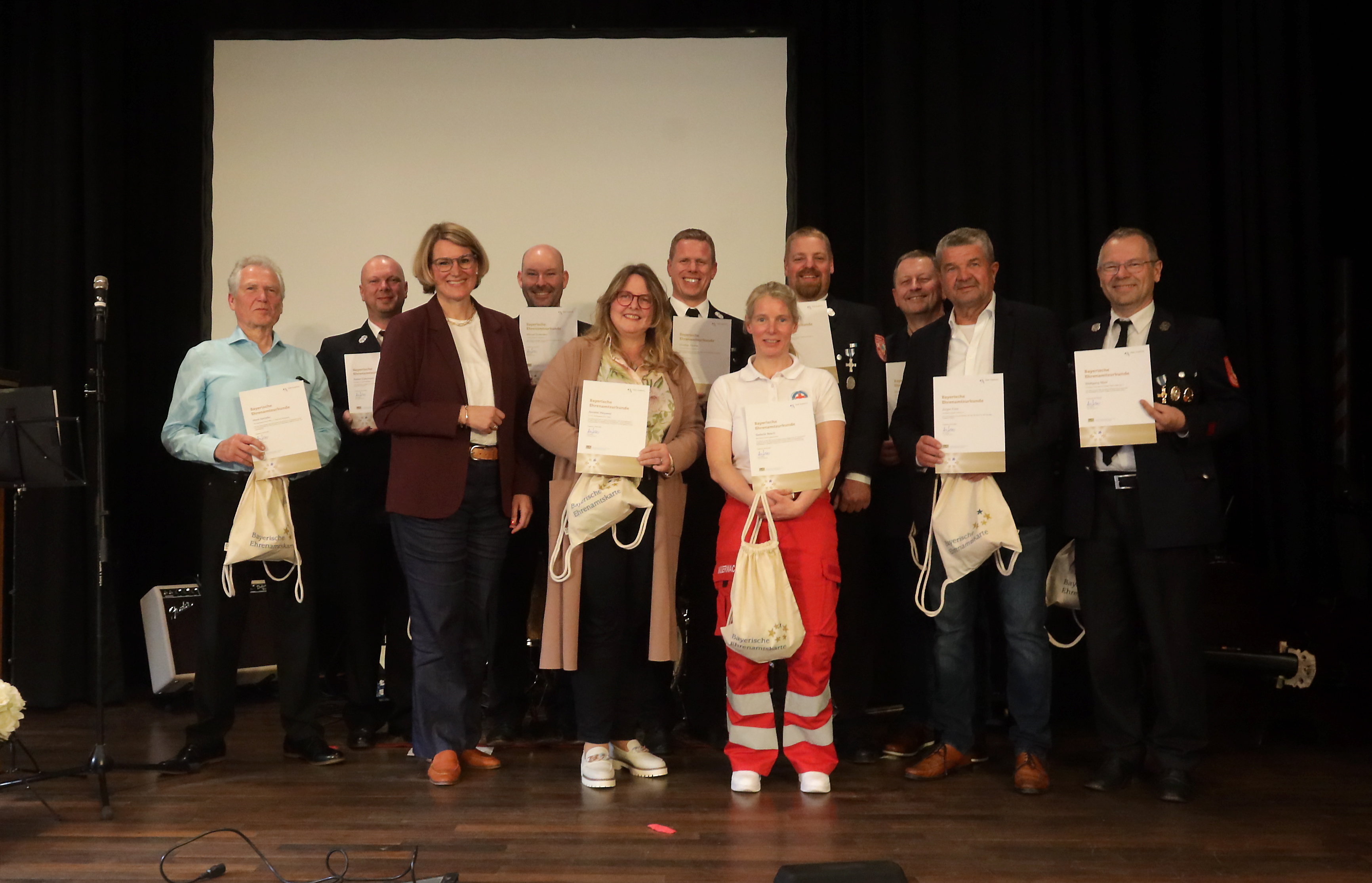 Oberbürgermeisterin Eva Weber steht neben etwa 10 Personen. Die meisten Leute halten eine Urkunde in der Hand
