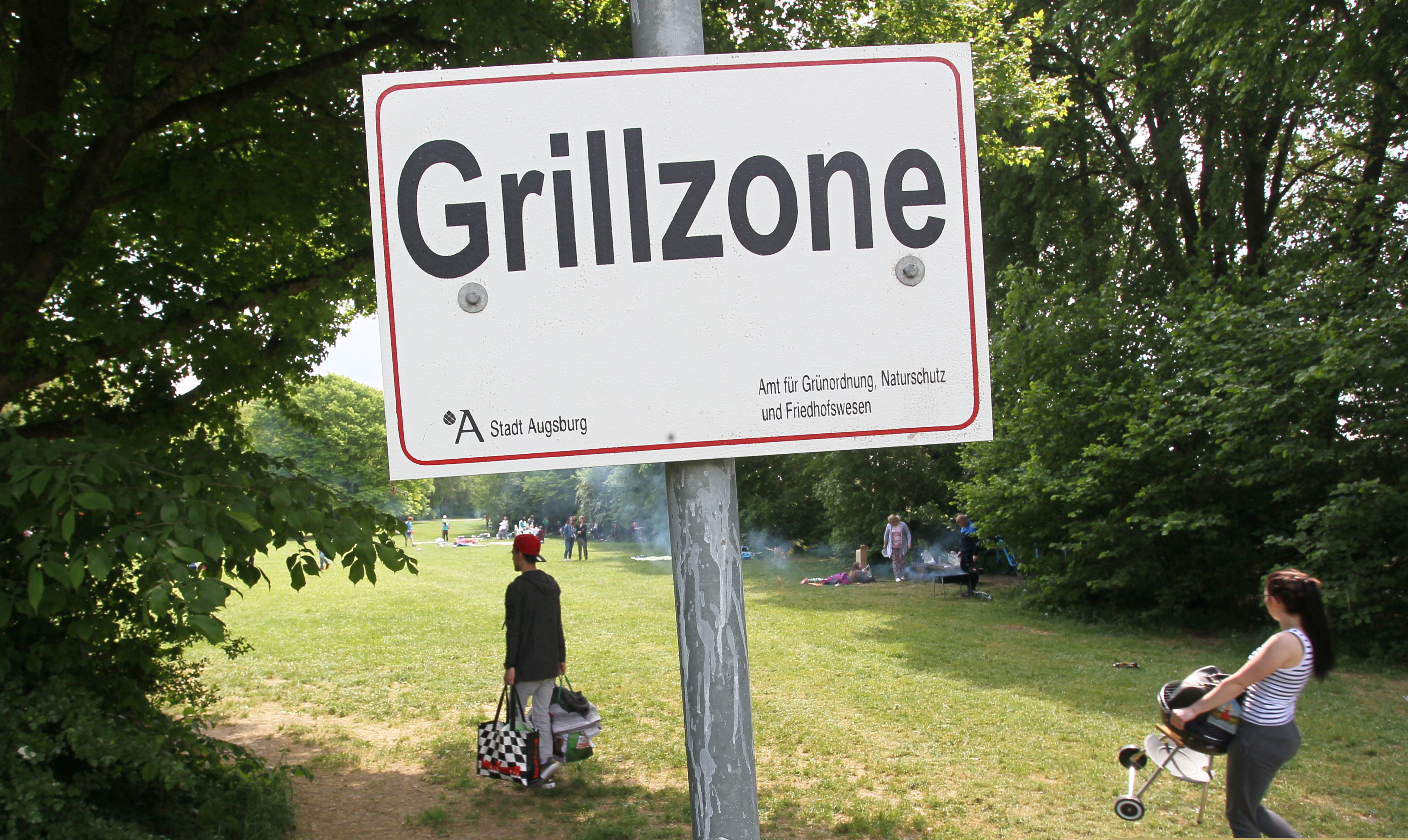 Schild in Grünanlage mit der Aufschrift "Grillzone"
